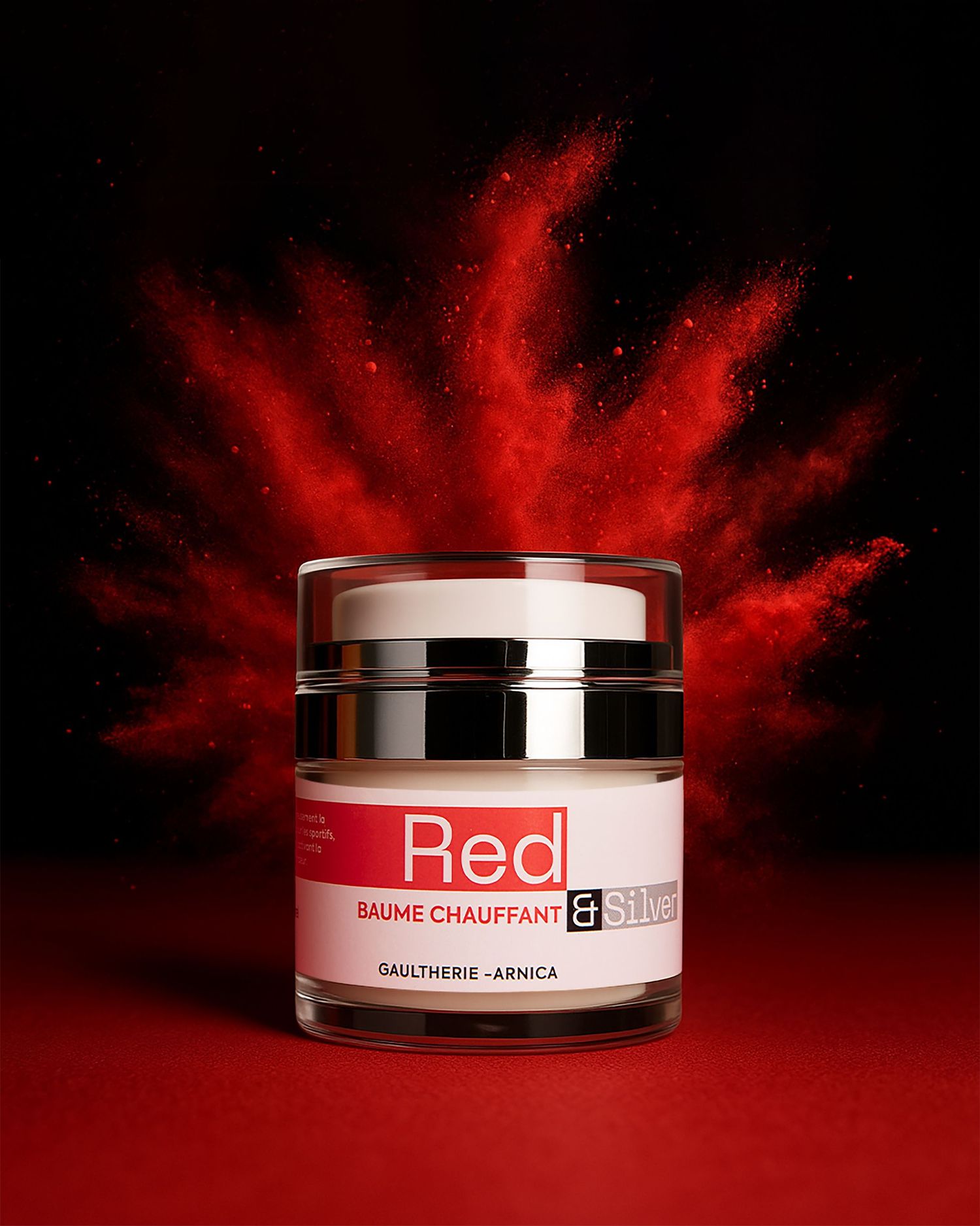 Red warming balm jar by Red and Silver surrounded by red powder explosion on dark background.