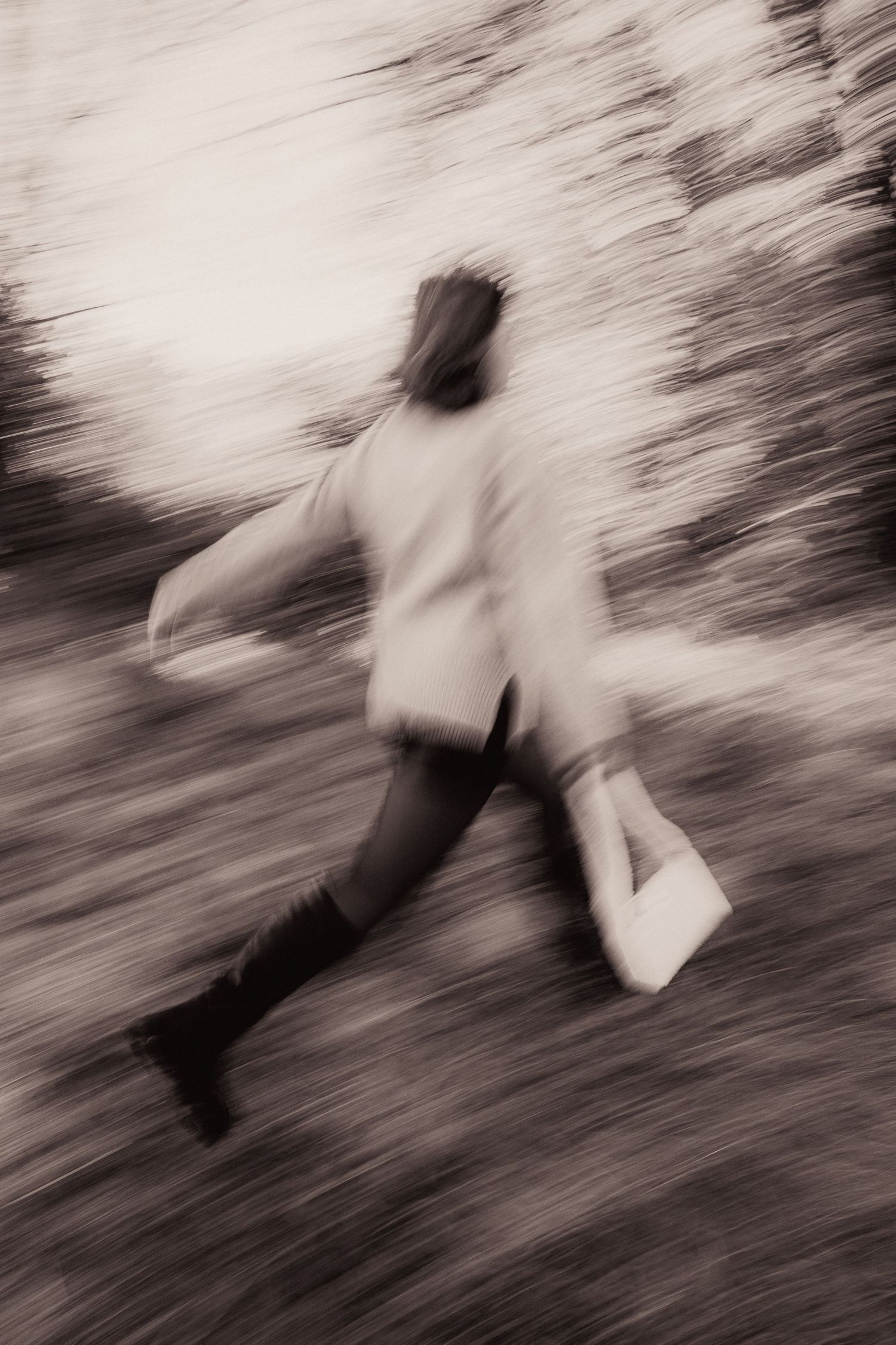 Blurred sepia action shot of a person running through a forest carrying a white bag.