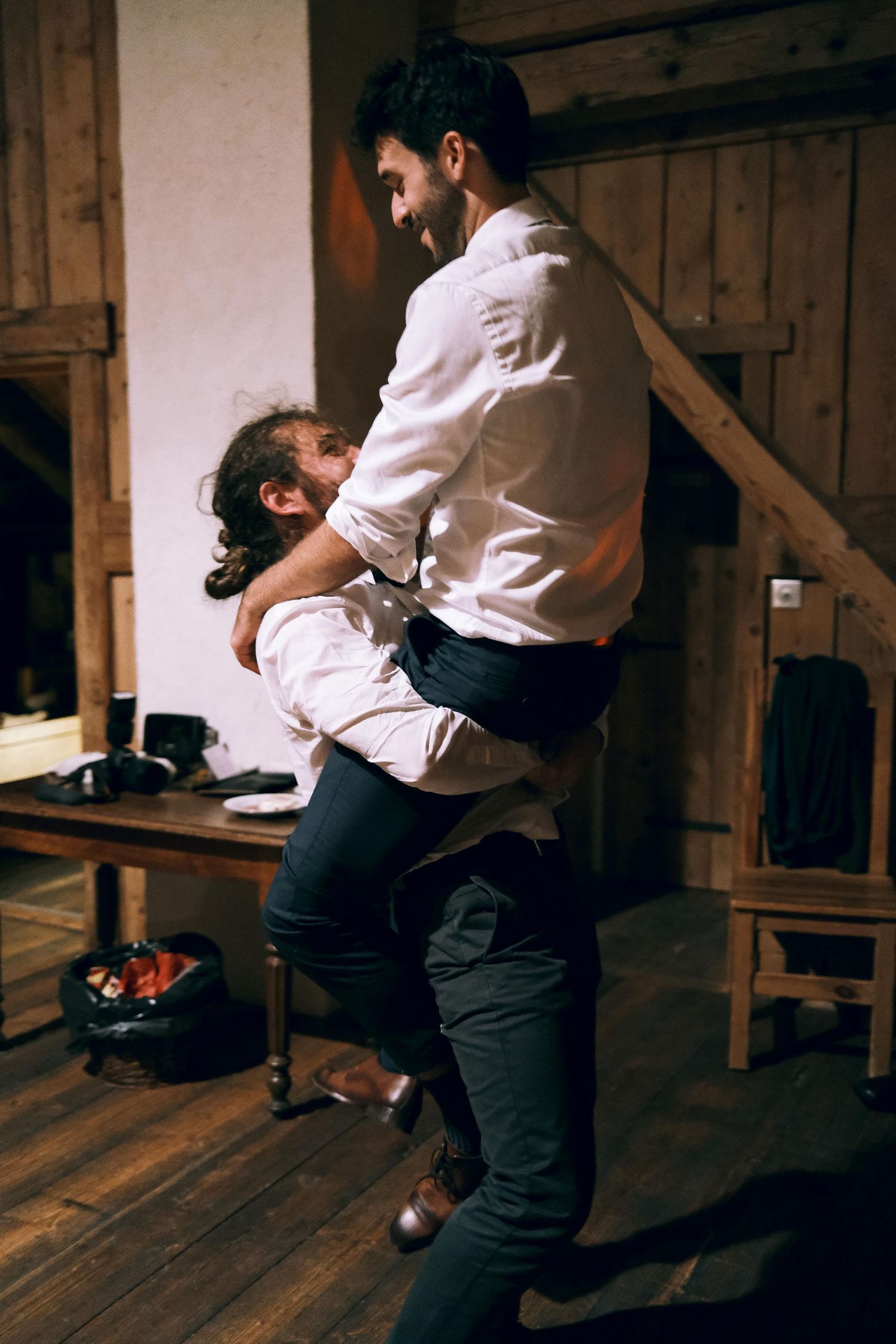 Couple sharing an intimate dance in a rustic wooden barn venue during a wedding reception.