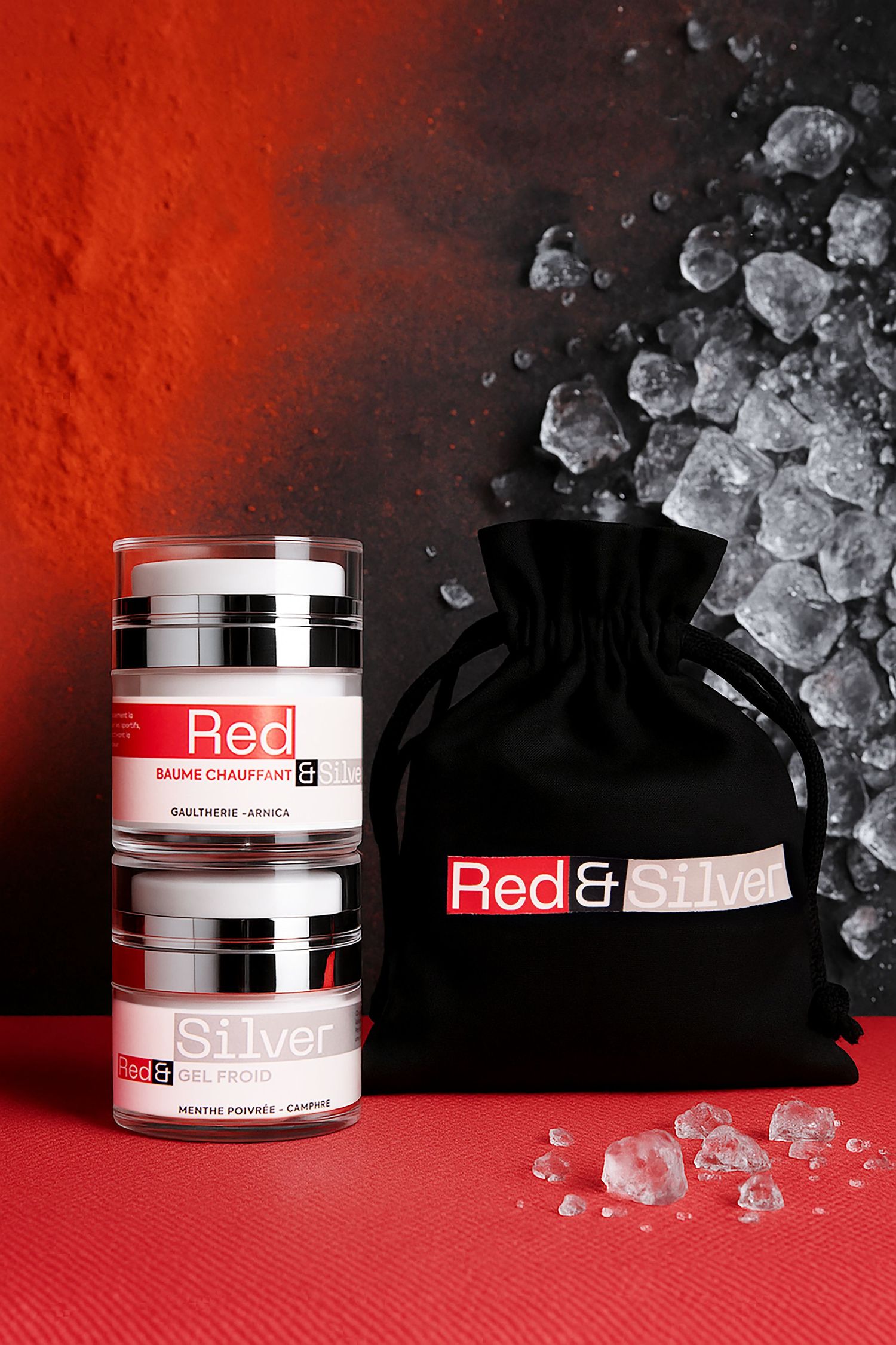 Red and Silver warming balm and cooling gel set with black velvet pouch on red background.