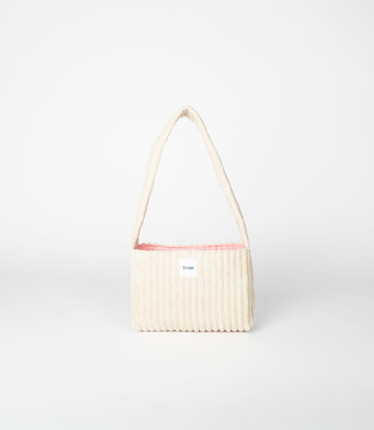 Cream quilted ribbed shoulder bag with pink interior lining and knotted strap, featuring small brand label.