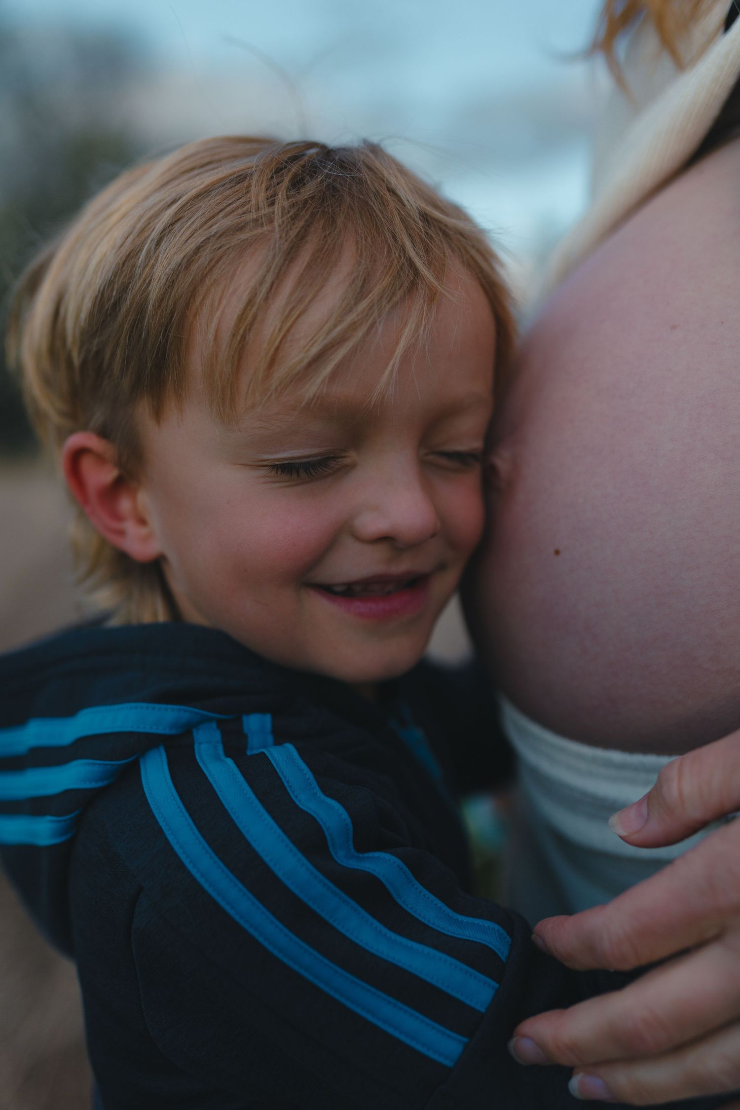 Expecting mother with son embracing belly during lifestyle maternity session