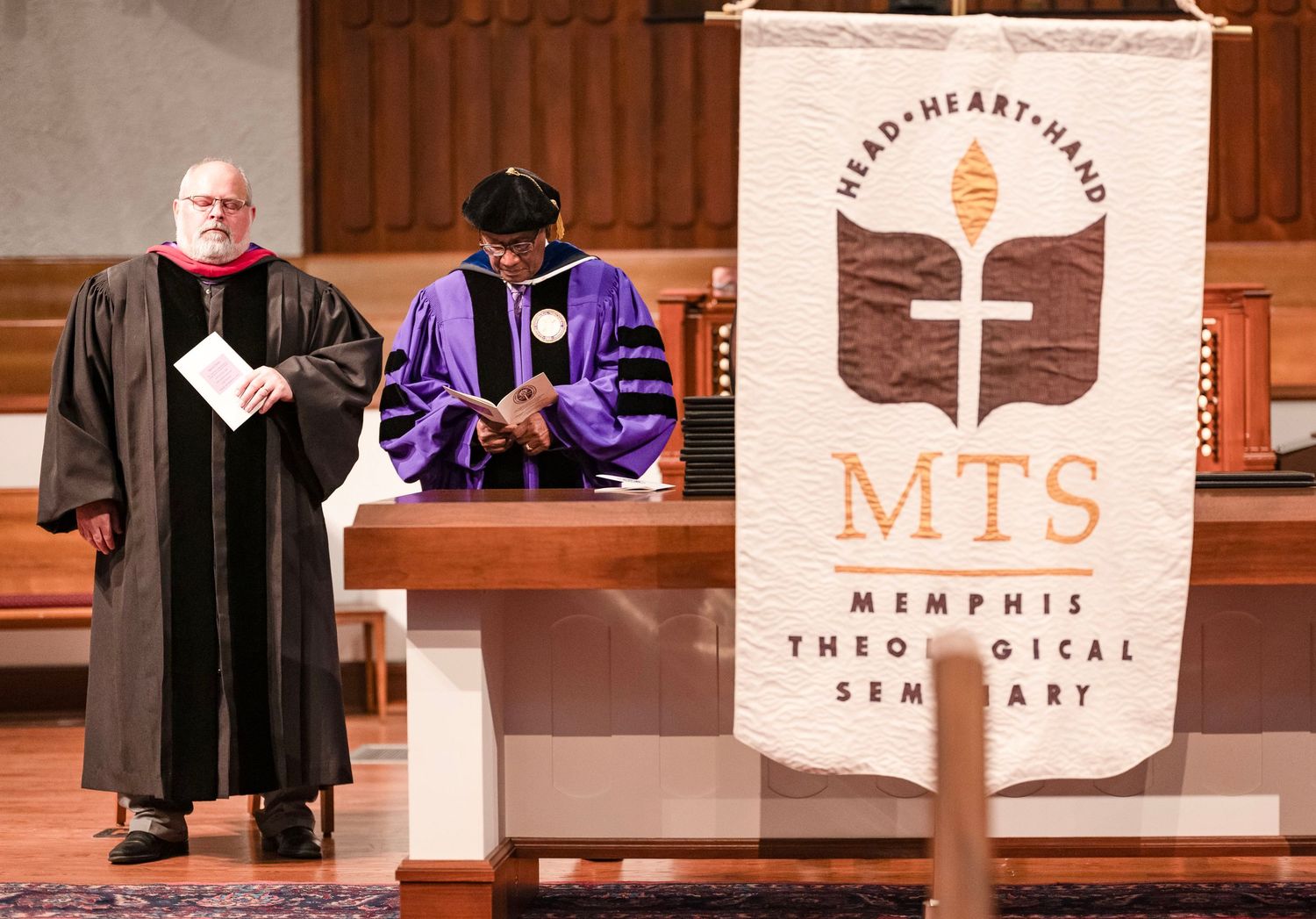 Two clergy members stand at the altar during a Memphis Theological Seminary ceremony.