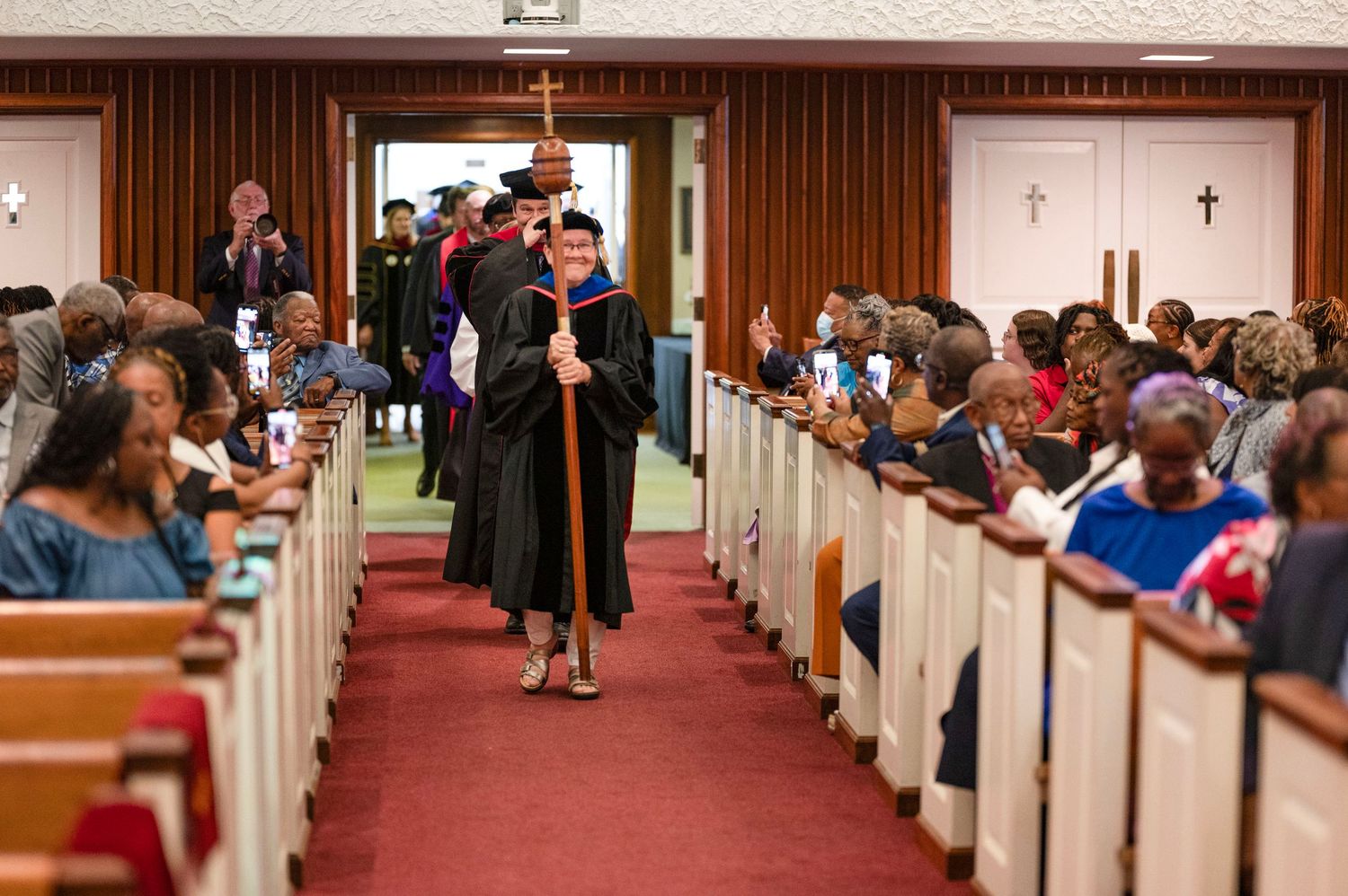 Academic procession walking down church aisle during graduation ceremony.