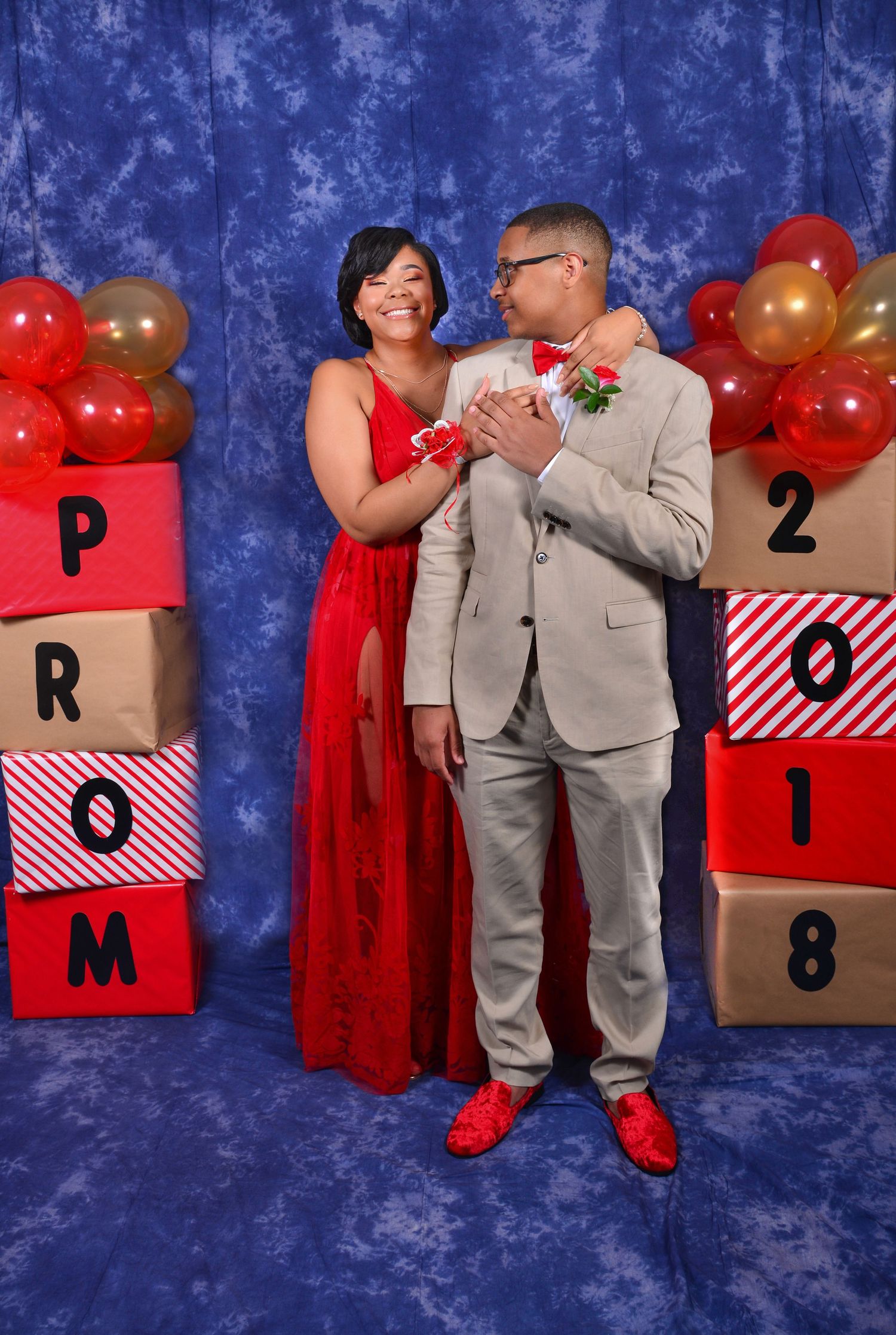 A couple shares a romantic moment at Prom 2018, woman in red gown and man in tan suit.