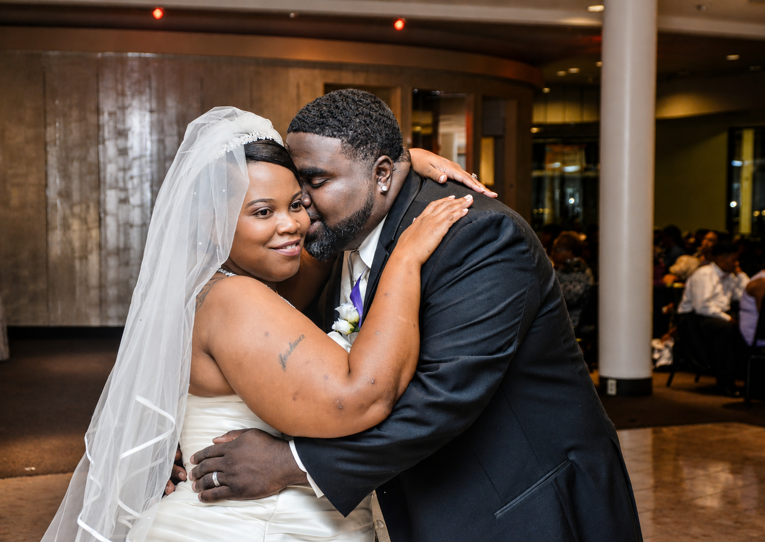 A bride and groom share a tender embrace and kiss during their wedding reception.