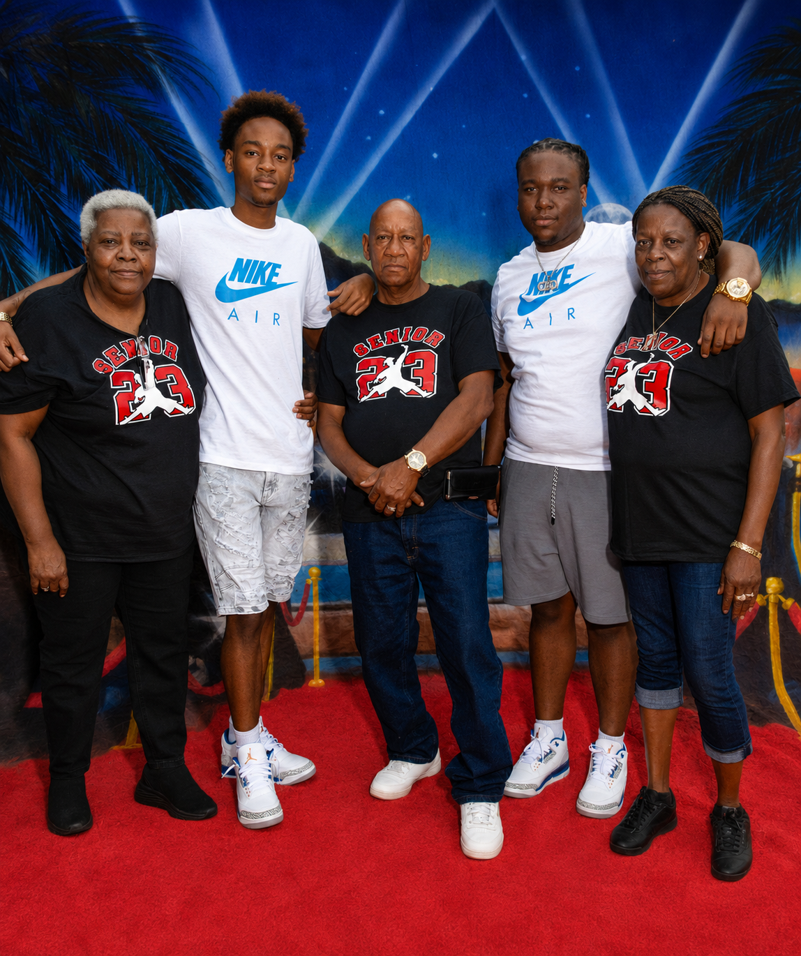 Family of five posing on red carpet wearing matching Jordan brand black t-shirts.