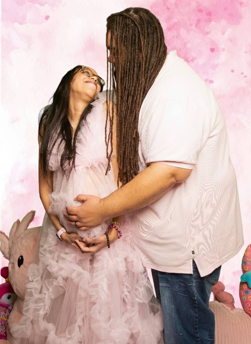 Couple sharing a tender moment with man embracing pregnant woman in pink gown at shower.