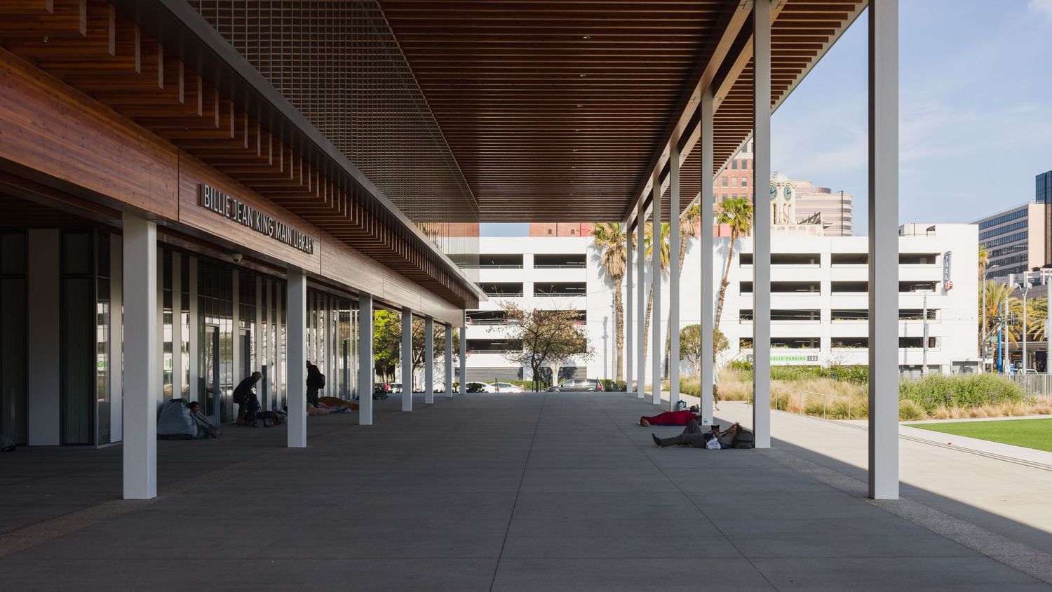 Numerous homeless people under the eave of the Billie Jean King Main Library in Long Beach California