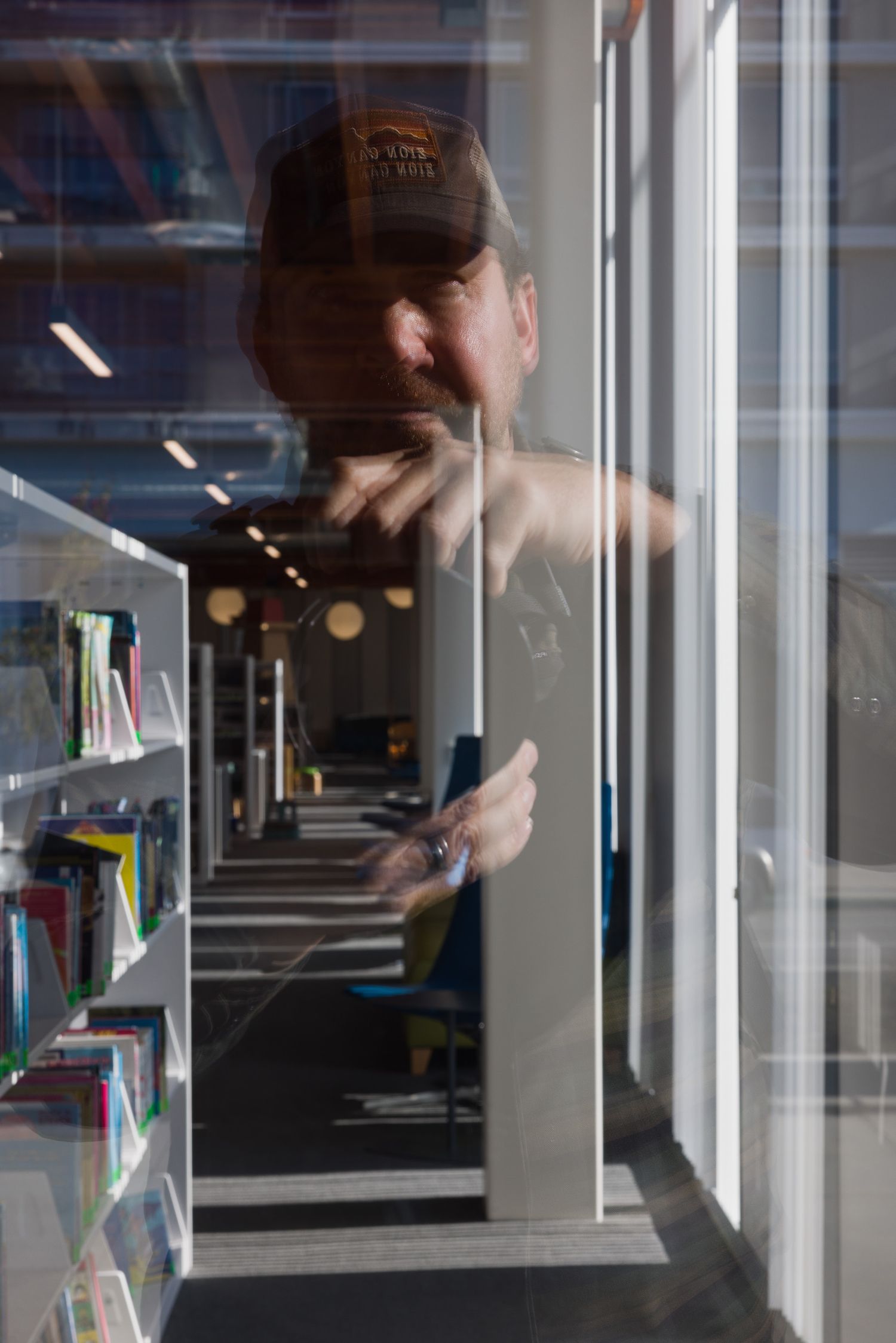 Photographer Colin Robertson reflected in a window of the Billie Jean King Main Library in Long Beach California