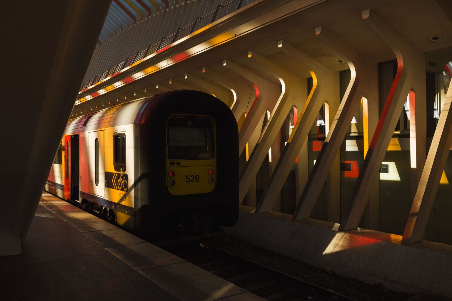 Train lit by red and yellow light from Daniel Buren artwork at Liège-Guillemins railway station, architecture by Santiago Calatrava