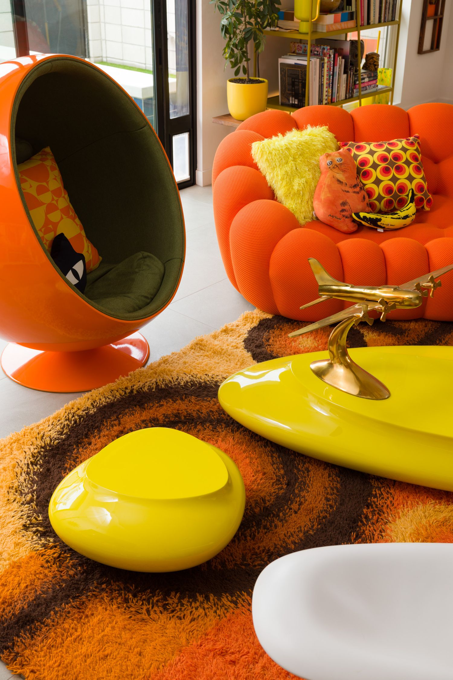 bright orange ball chair and sofa with yellow accents in a jet-set living room detail