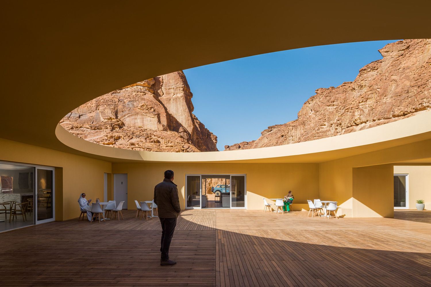 The now tan colored Desert X 2026 Visitor Center in AlUla Saudi Arabia looking out of the oculus, architecture by kwy.studio