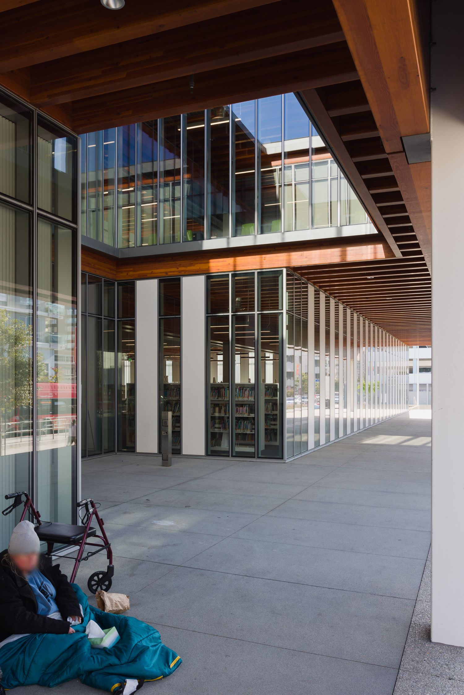 An unhoused person under the eave of the Billie Jean King Main Library