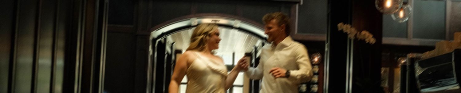 Bride and groom sharing joyful moment in dimly lit elegant venue doorway.