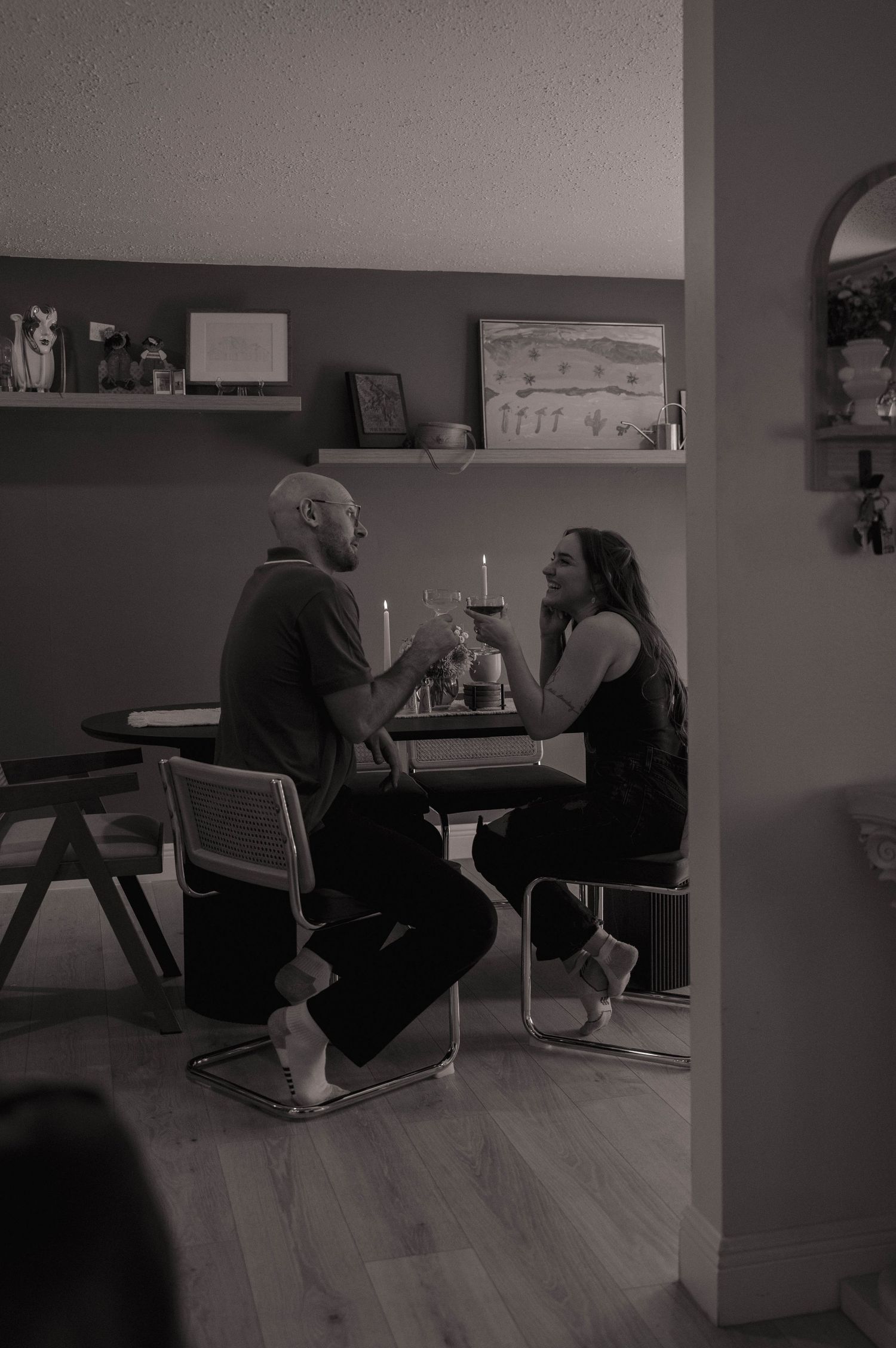 Black and white photo of a couple sharing a candlelit dinner conversation at a dining table.