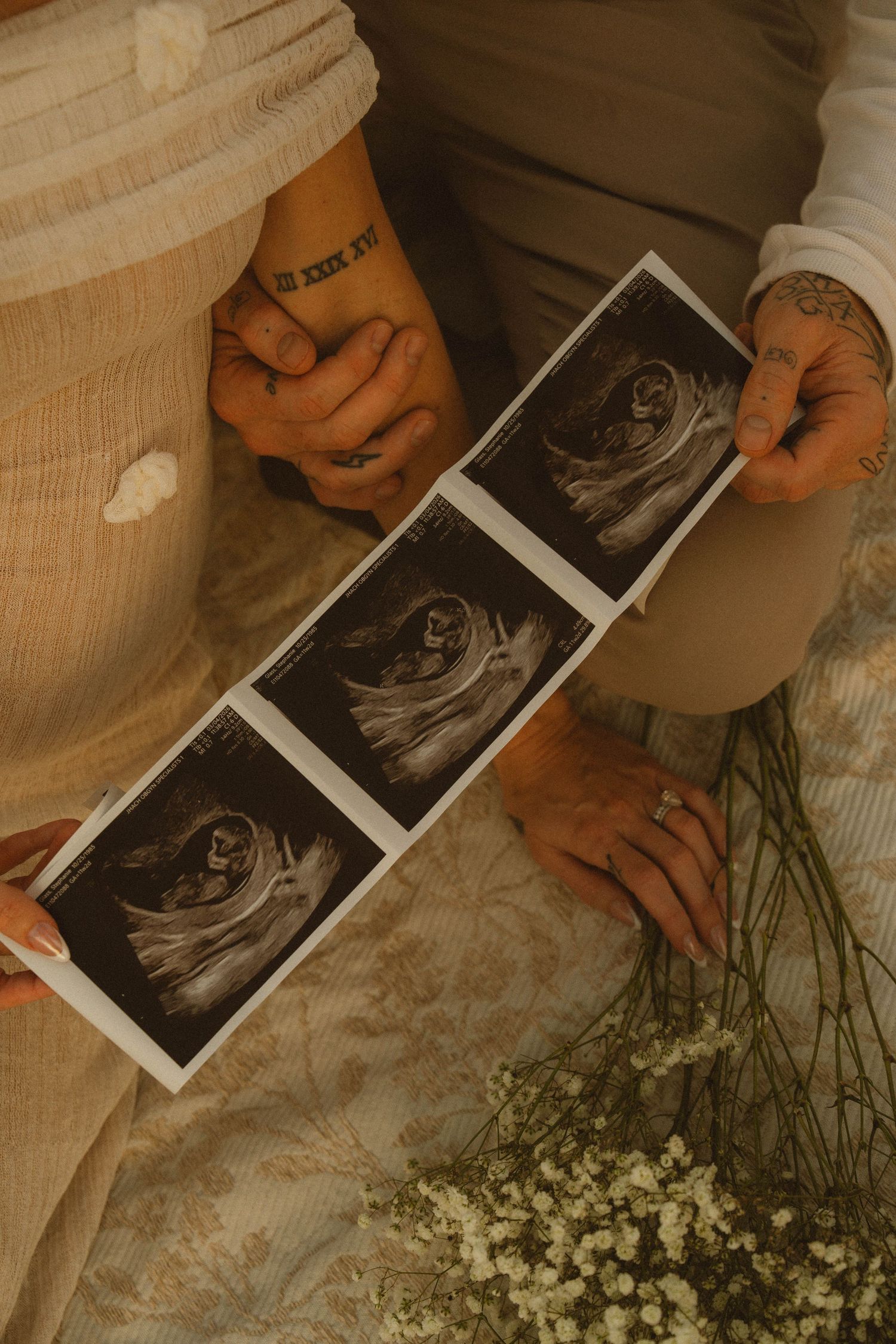 Couple holding ultrasound photos together, celebrating pregnancy announcement with baby sonogram images.