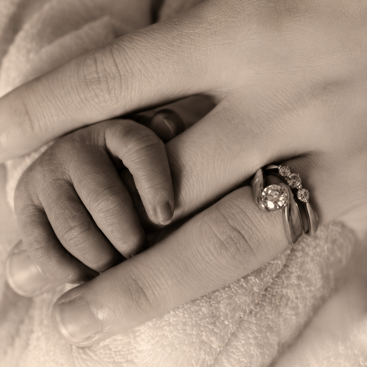 mother’s hand beside a newborn’s tiny fingers