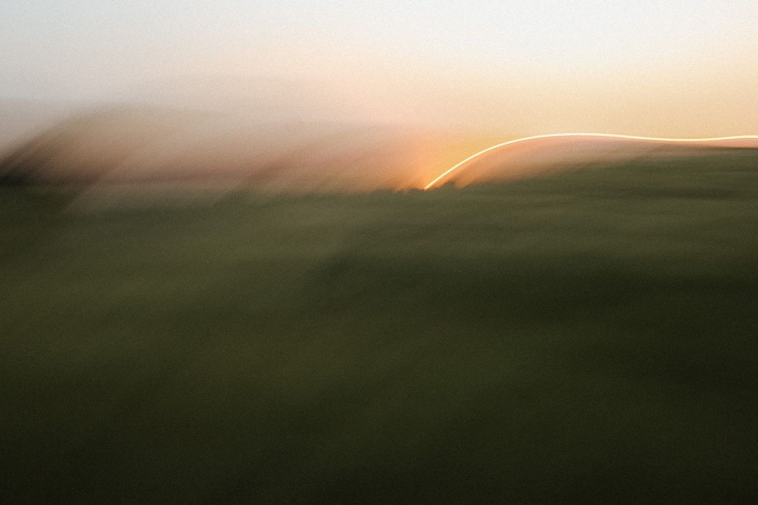 Abstract motion blur landscape of green hills at golden sunset with streaking light effect.