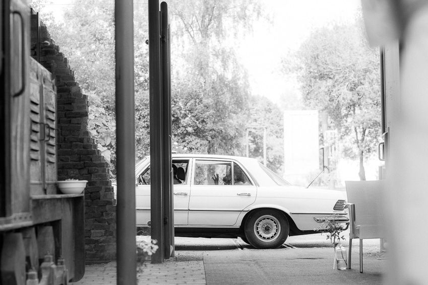 Classic vintage white car parked outside wedding venue in black and white photo.