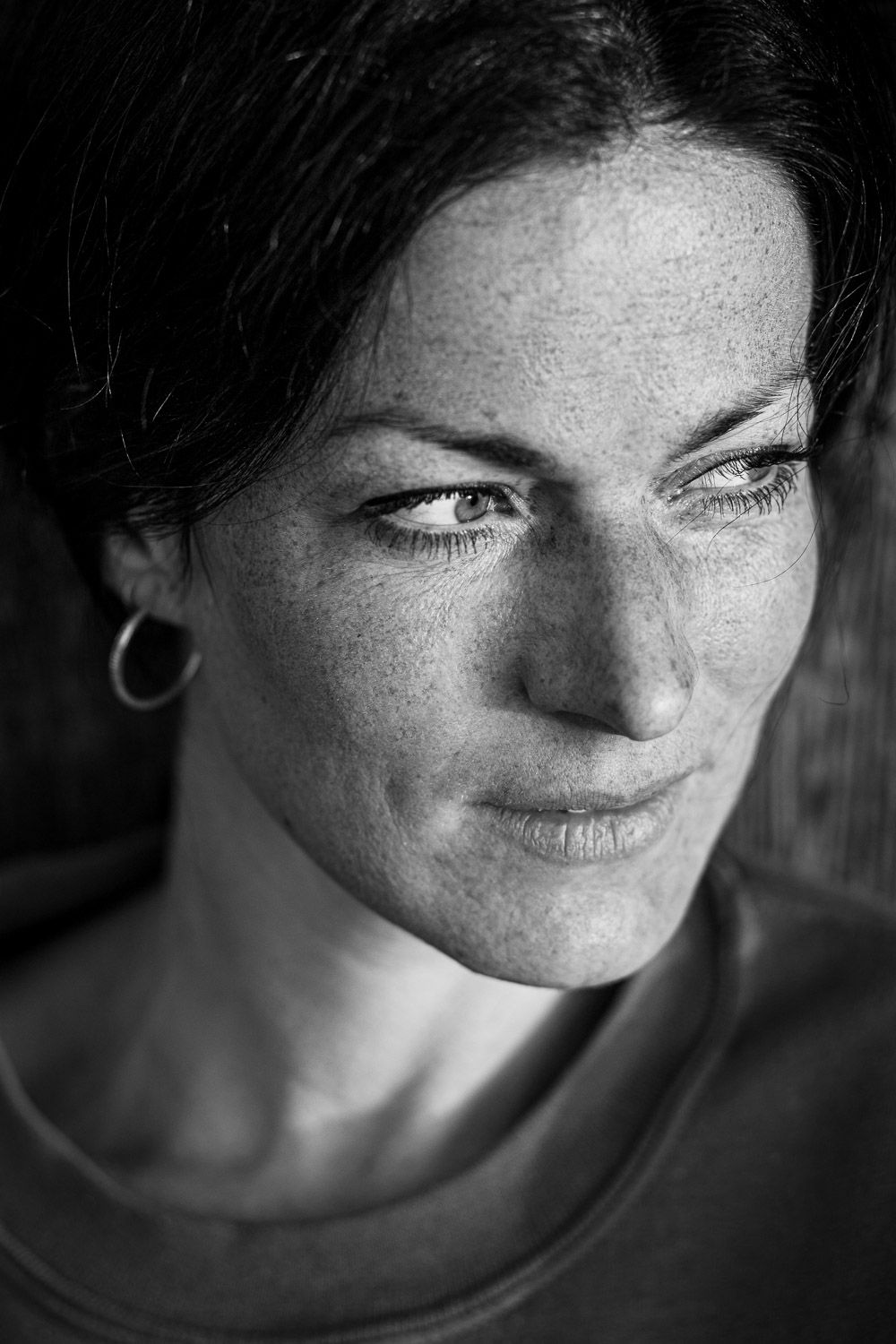 Black and white close-up portrait of a freckled woman with hoop earring.
