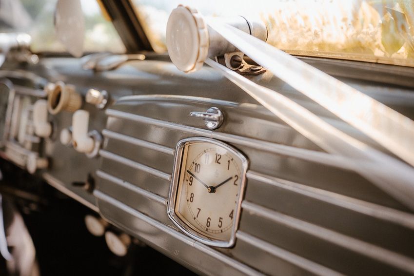 Close-up of vintage classic car dashboard featuring elegant analog clock and chrome details.