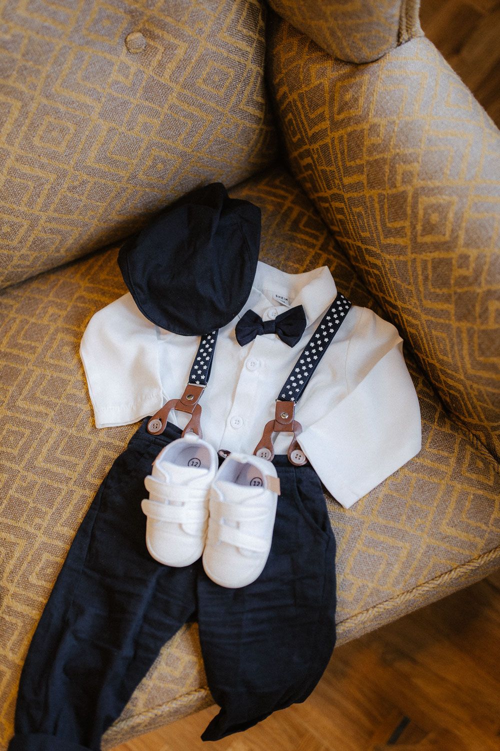 Adorable baby boy christening outfit with white shirt, suspenders, bow tie, cap, and white shoes.