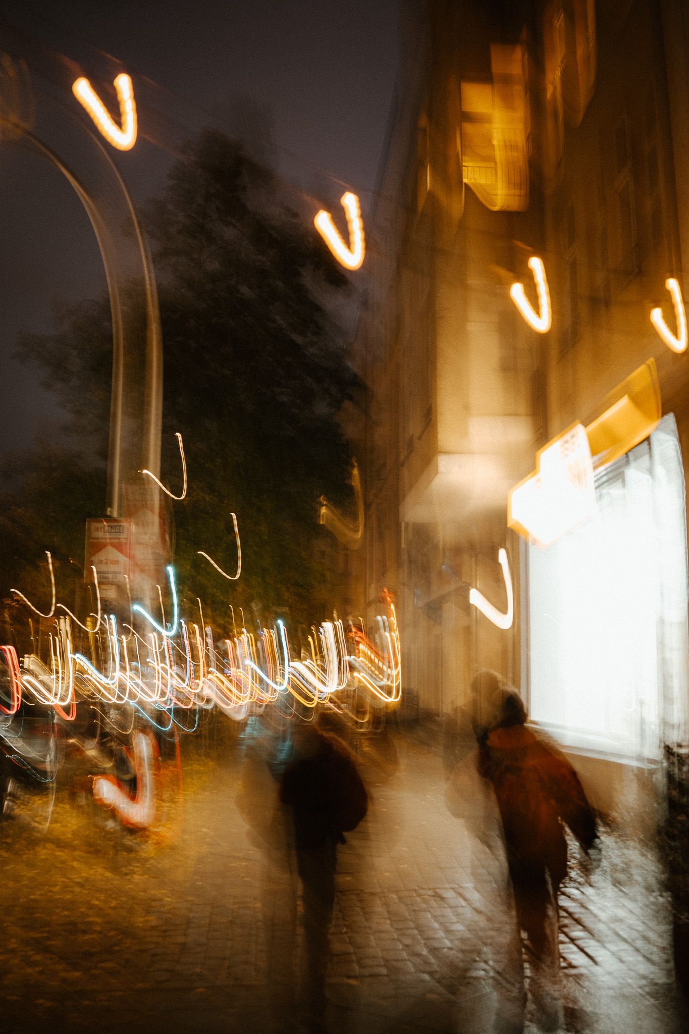 Long exposure night street photography showing blurred pedestrians and streaking city lights.