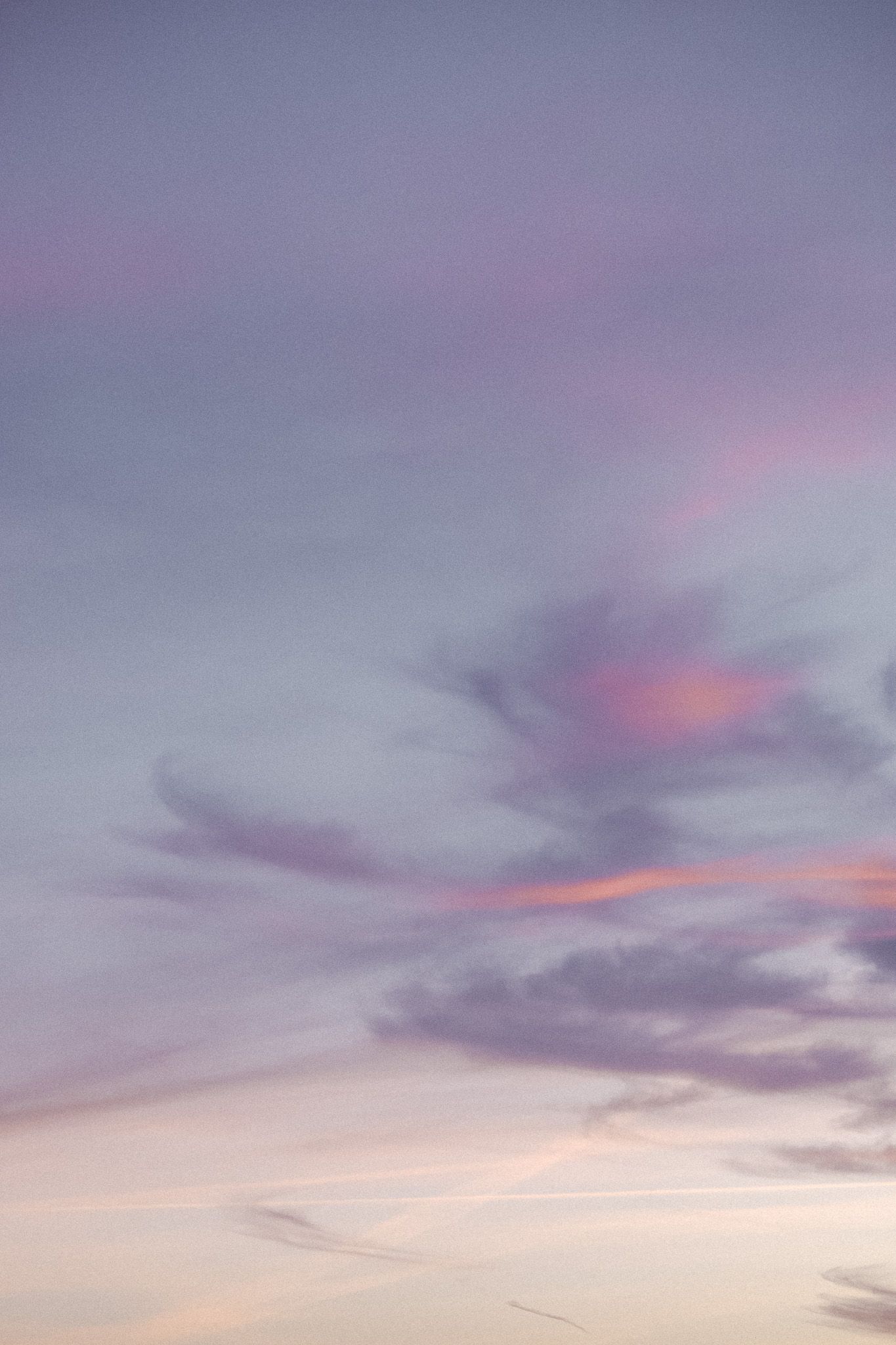 Soft purple and pink clouds drifting across a pastel twilight sky at dusk.