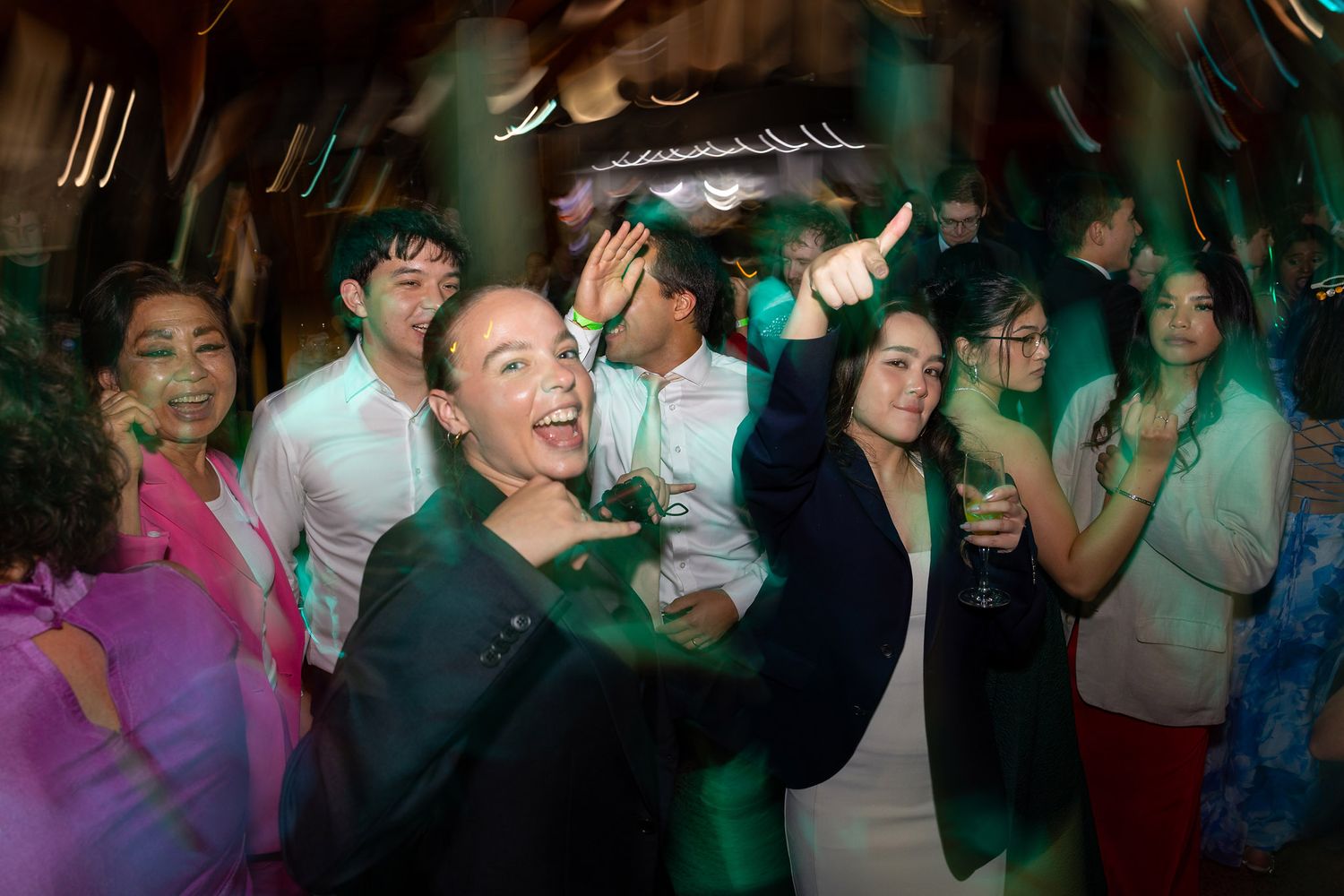 Excited guests dancing and celebrating at a lively indoor party event with colorful green lighting, modern event photography