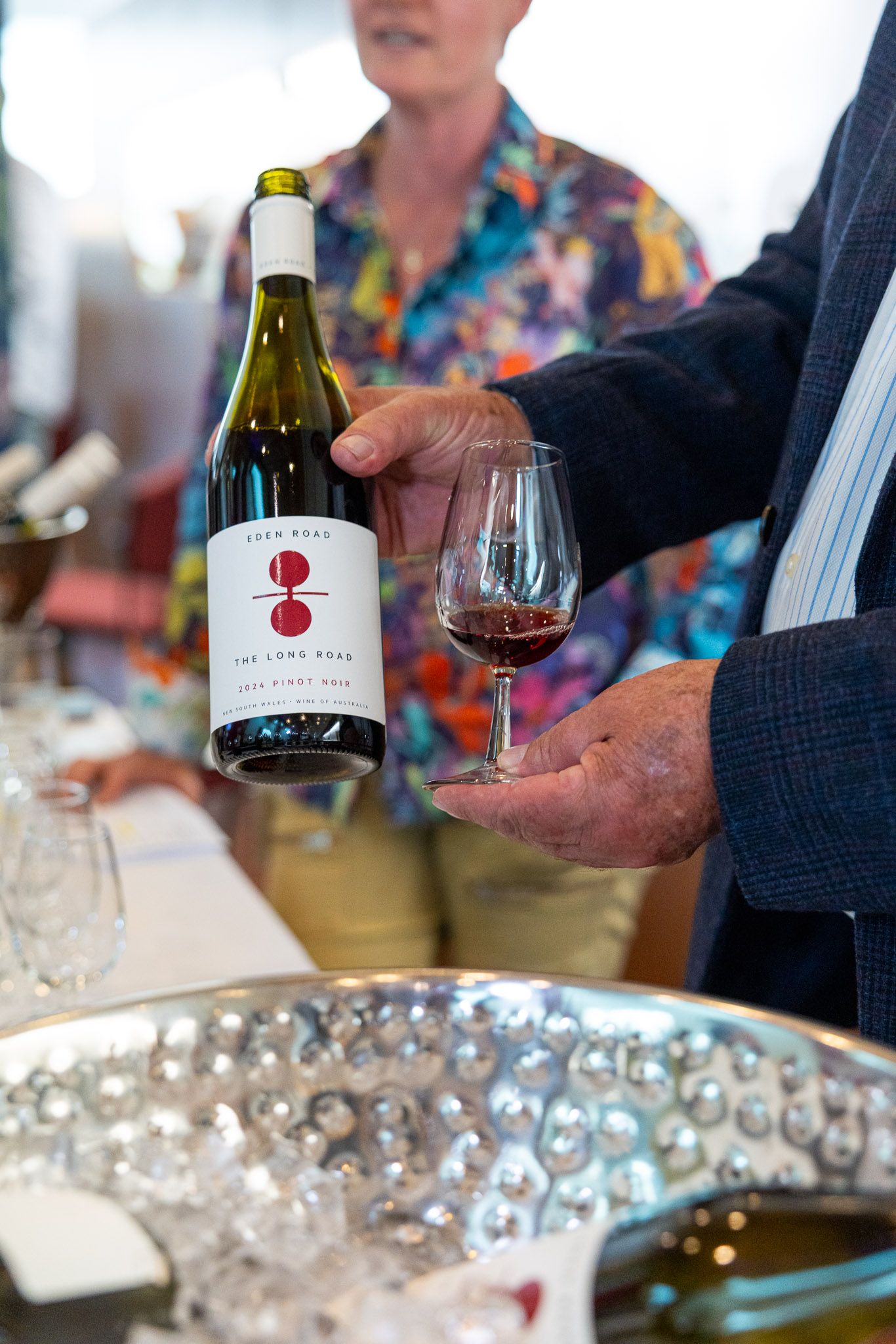 A man holds a bottle of wine to the camera at a tourism event at Parliament House, product and event photography