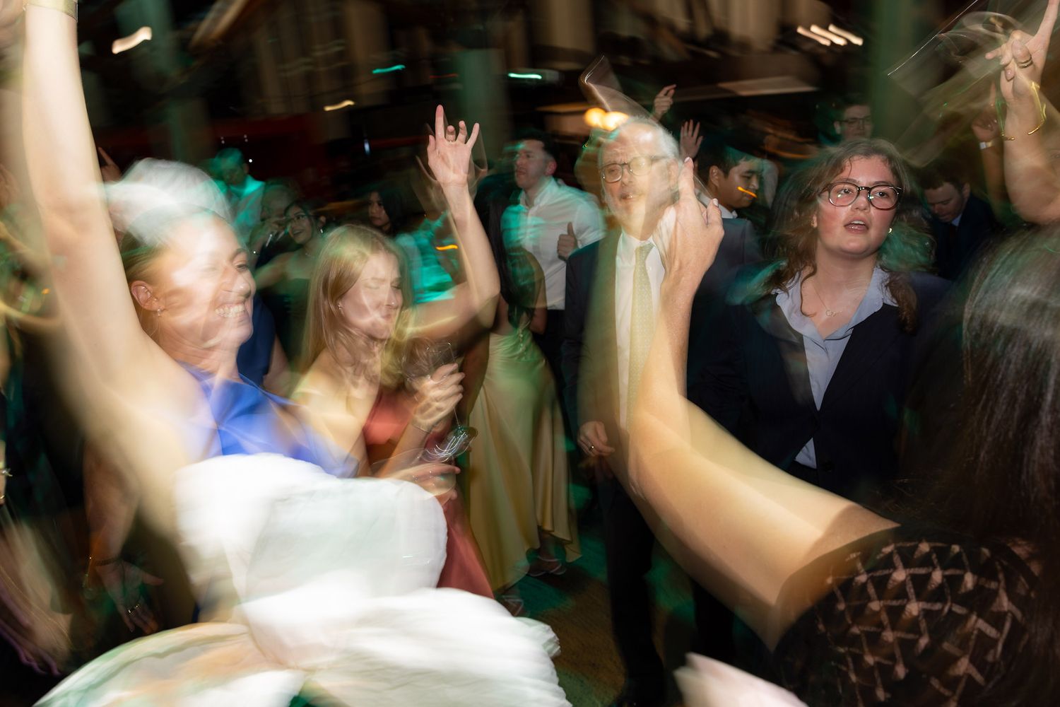 Lively wedding reception dance floor with guests dancing and celebrating under warm lights.