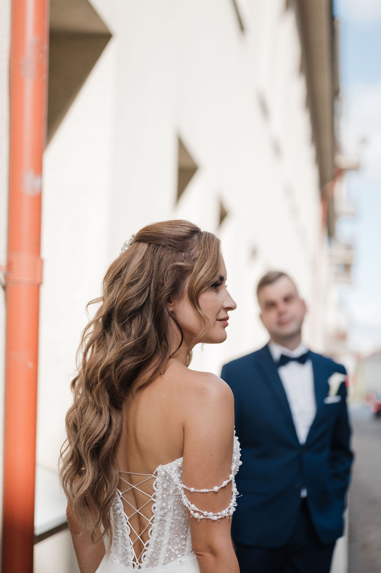 Nuotaka su suknele miesto gatvėje, jaunikis fone – vestuvių fotografija Lietuvoje