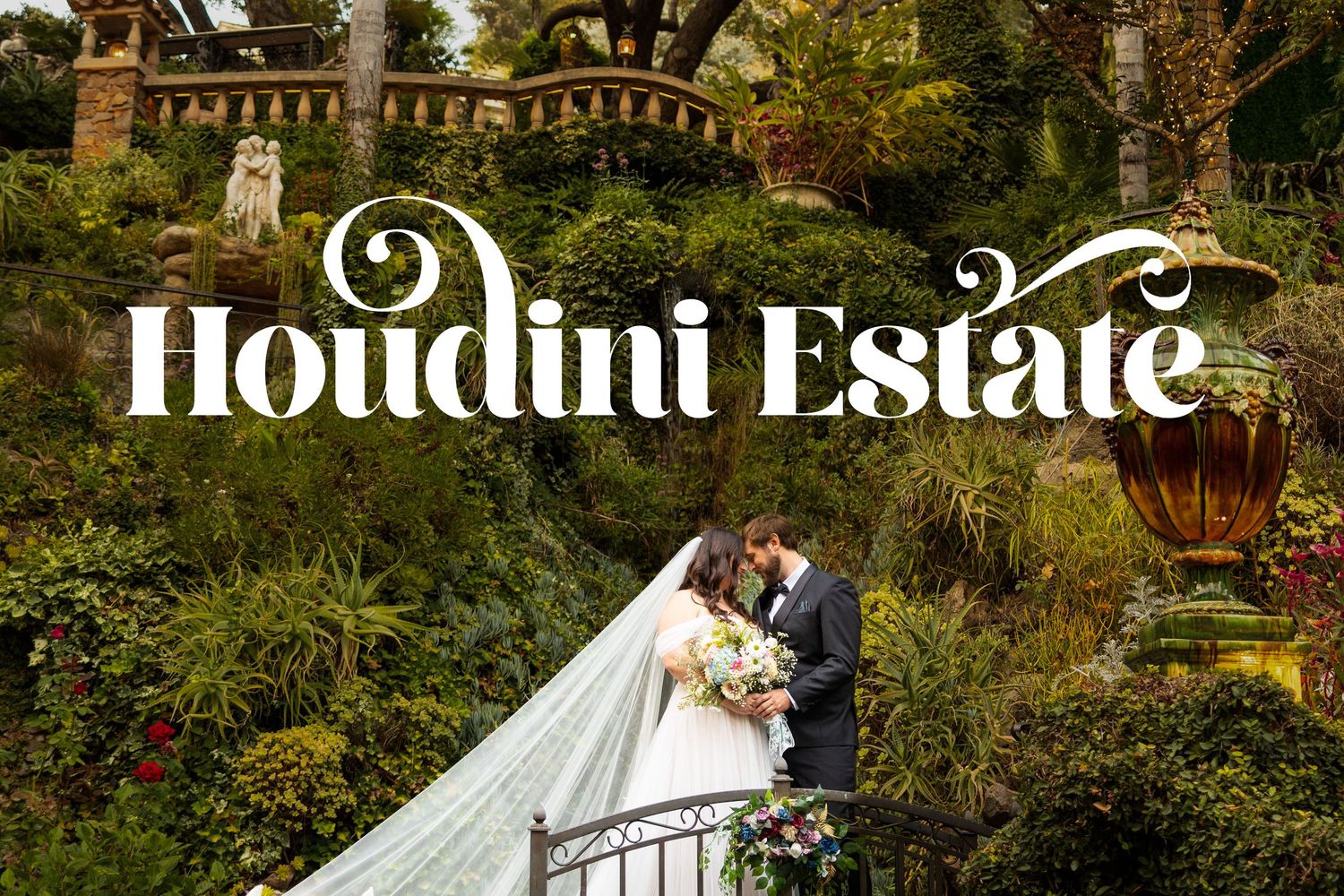 A romantic wedding couple embraces on the elegant steps of the historic Houdini Estate surrounded by lush gardens.