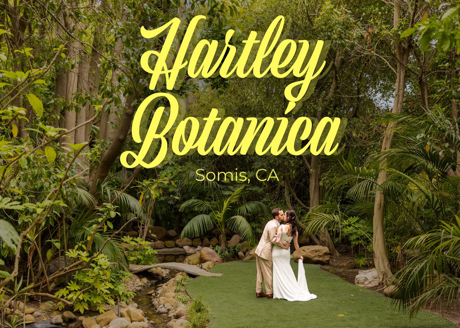 Two people in white attire embrace in a lush garden setting beneath yellow 'Hartley Botanica' signage in Somis, CA.