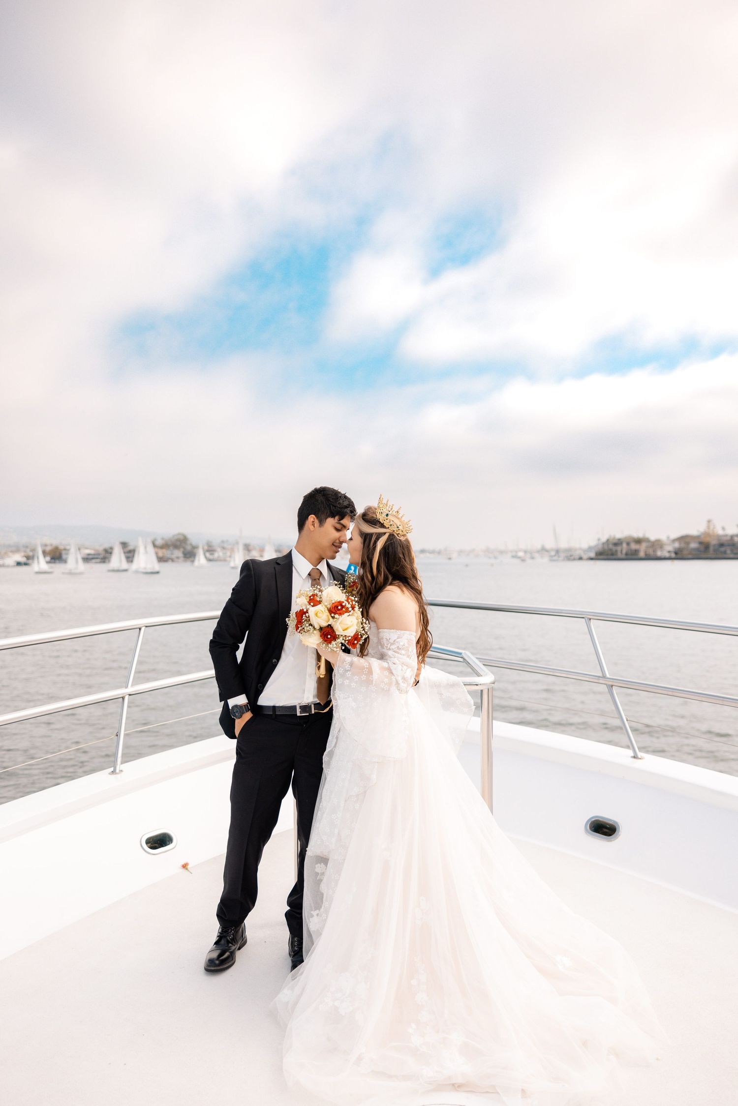 Couple in wedding attire share romantic moments on a bright white rooftop against a cloudy blue sky backdrop.