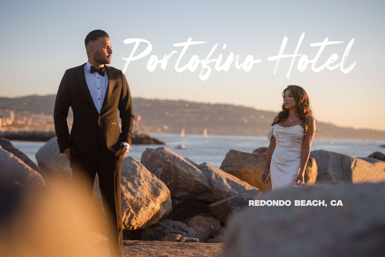 Sunset wedding photo of newlyweds posing on rocks at Portofino Hotel in Redondo Beach, California with ocean views.