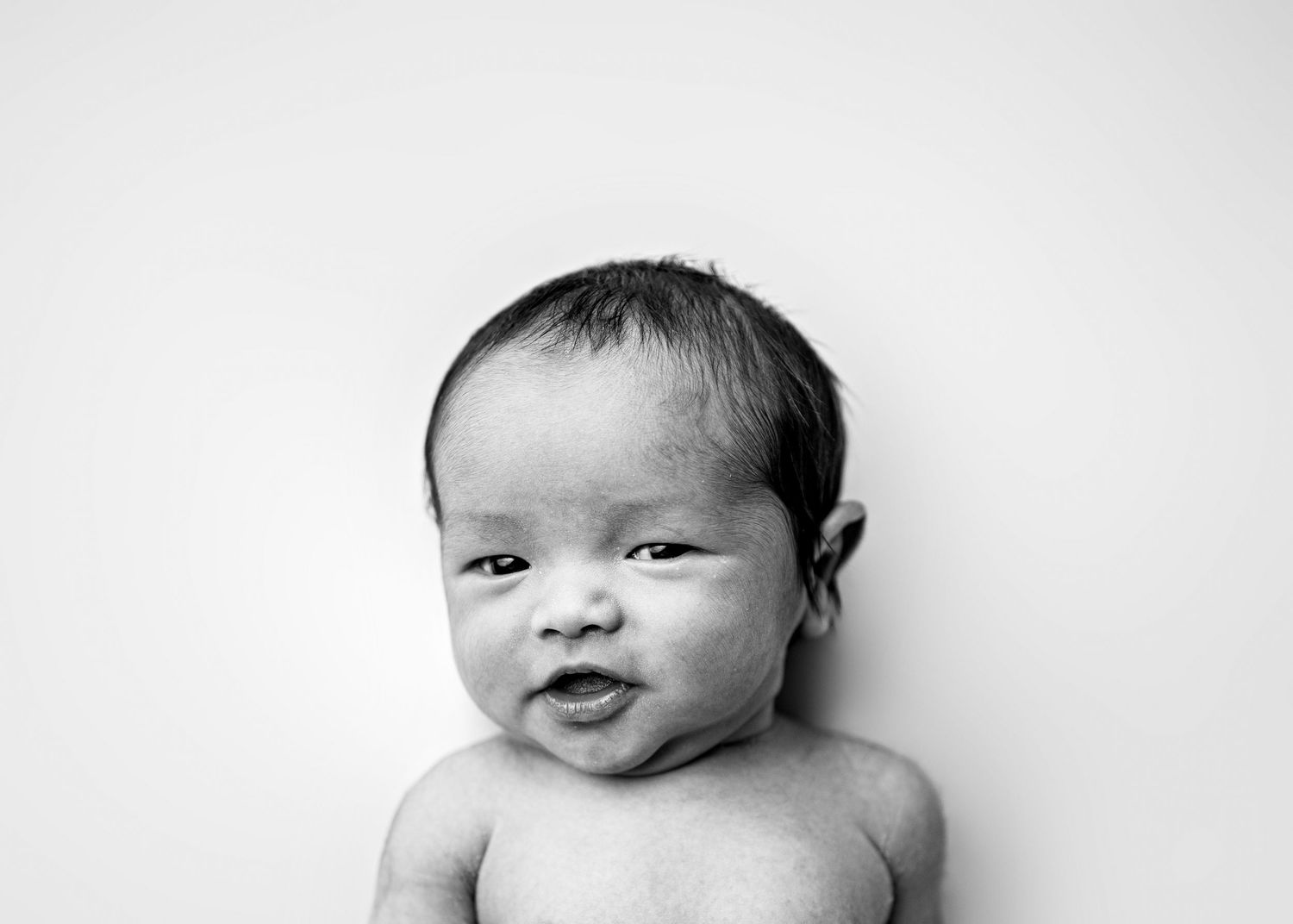 A black and white collage shows four close-up shots of a newborn baby from different angles.