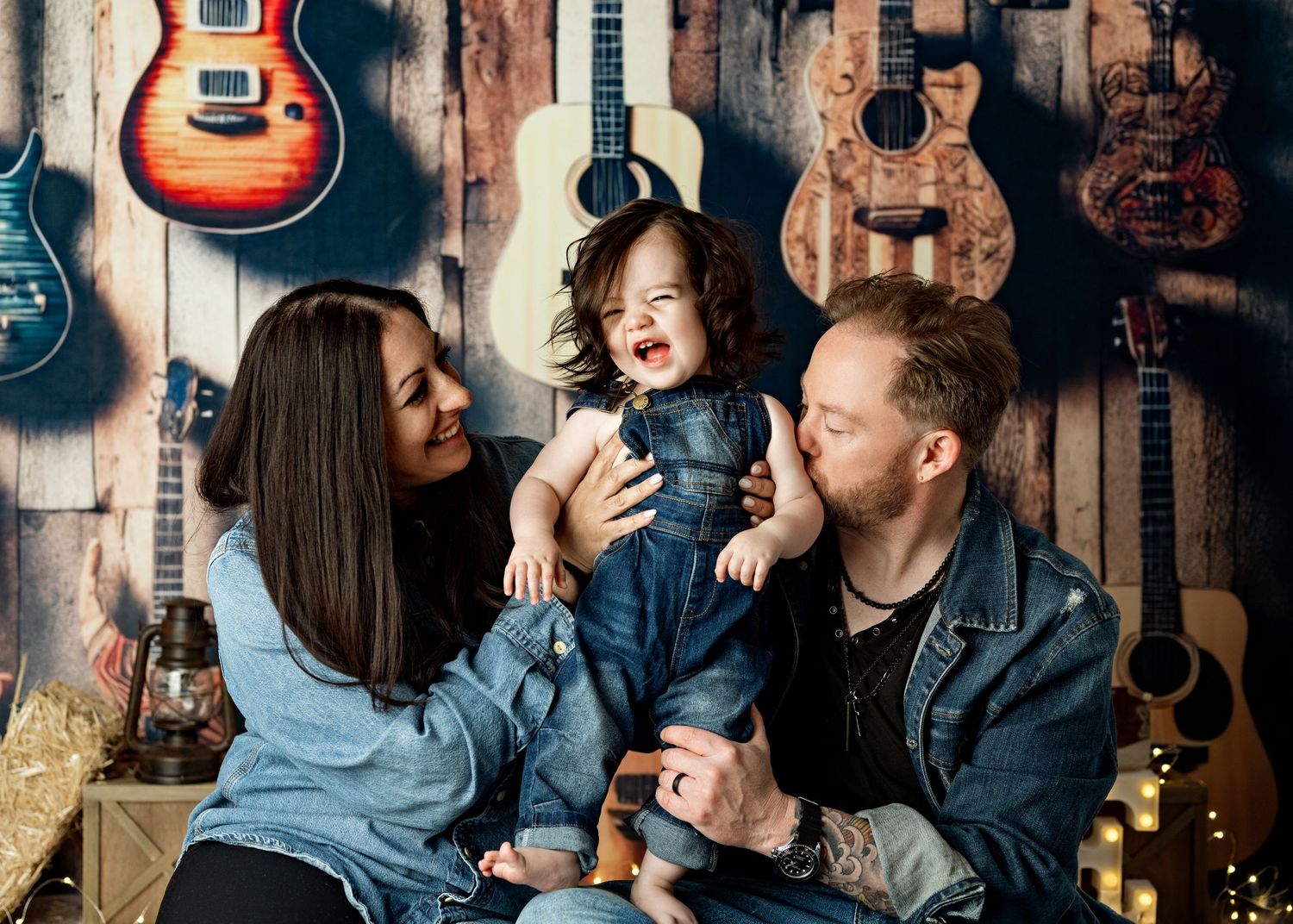 People share a joyful moment against a wall decorated with hanging guitars in a music-themed setting.