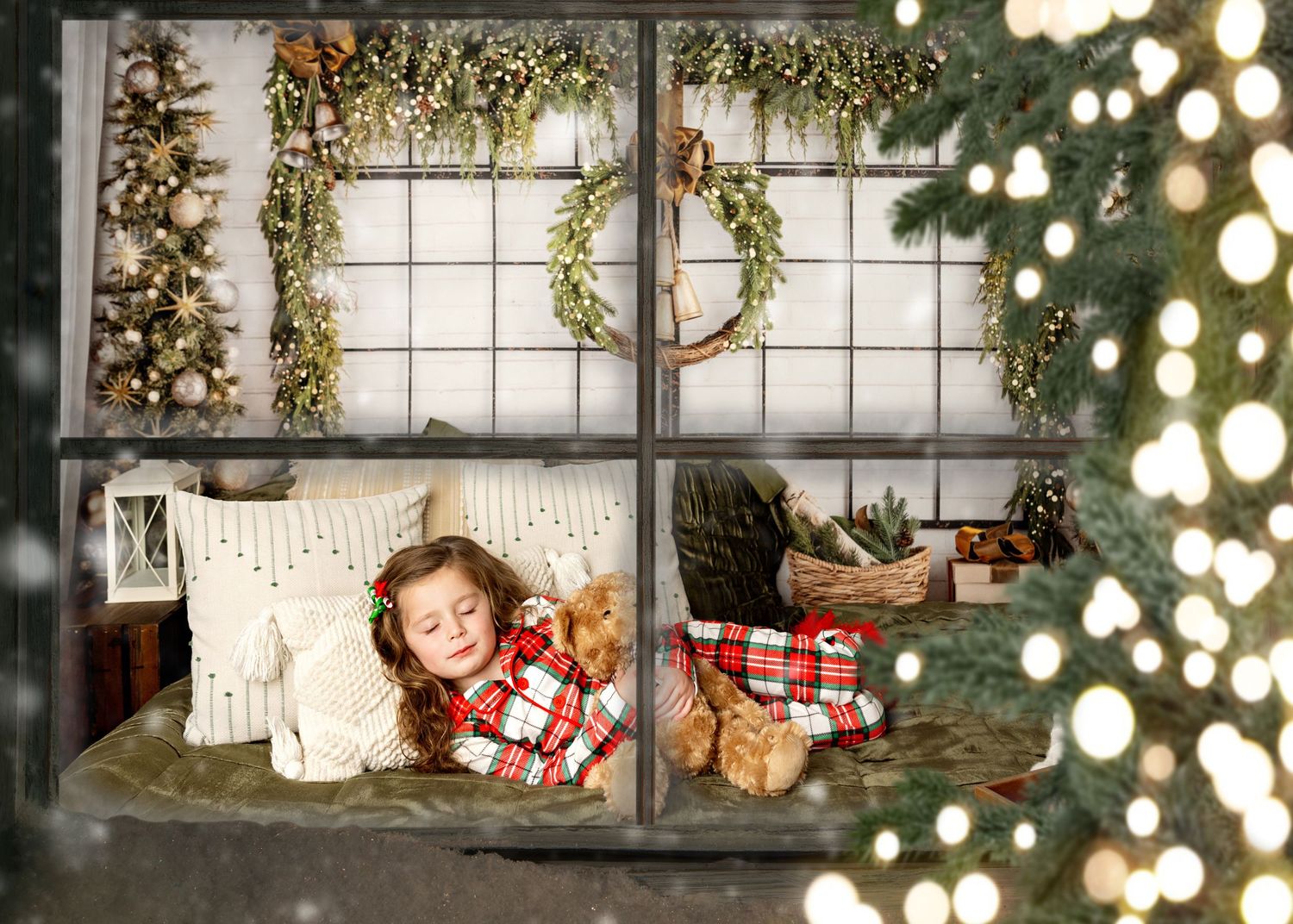 A rustic holiday window display featuring natural greenery, string lights and wrapped presents arranged on a windowsill.