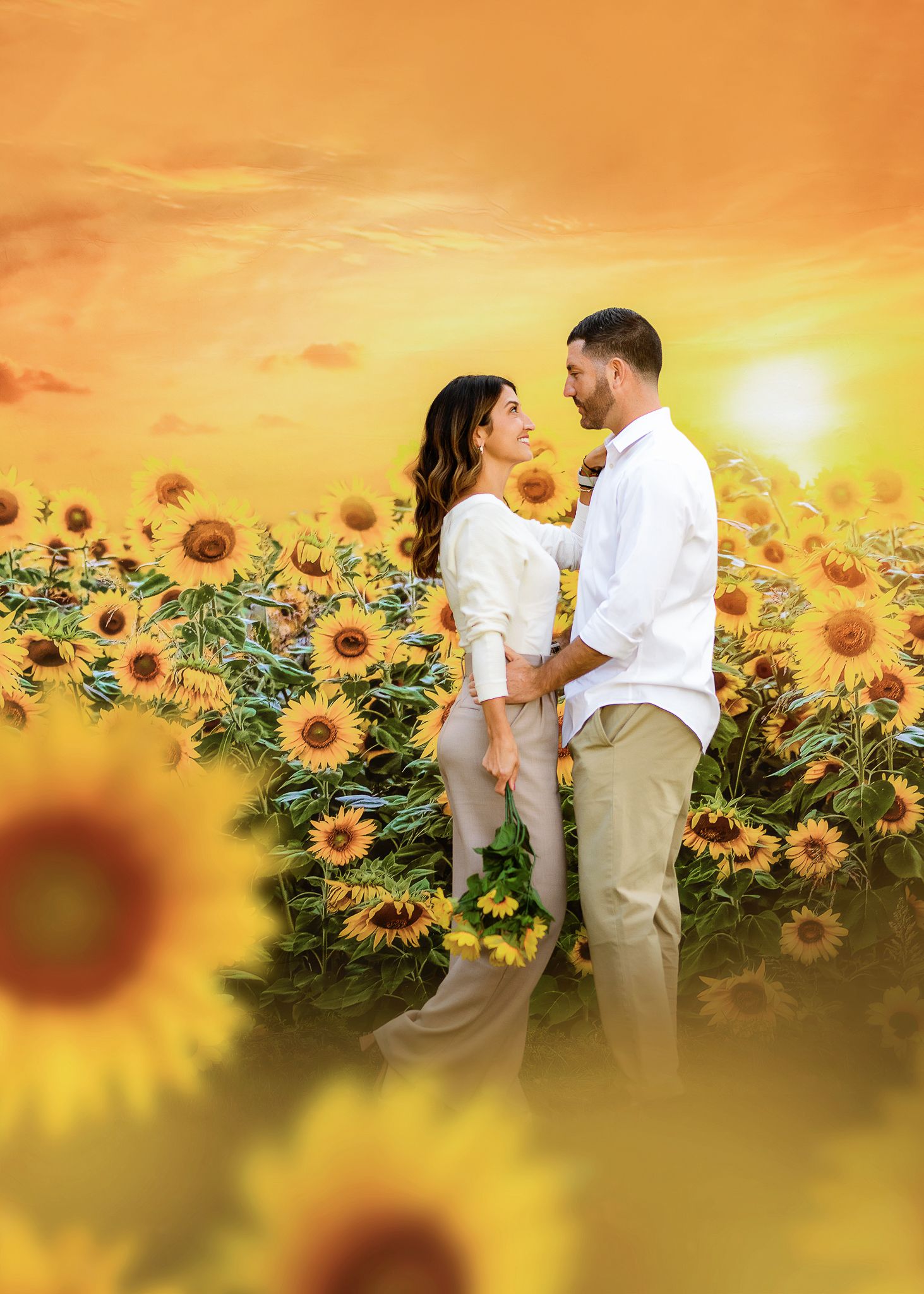 A romantic couple embraces in a sunflower field at sunset with golden light illuminating the dreamy summer scene.