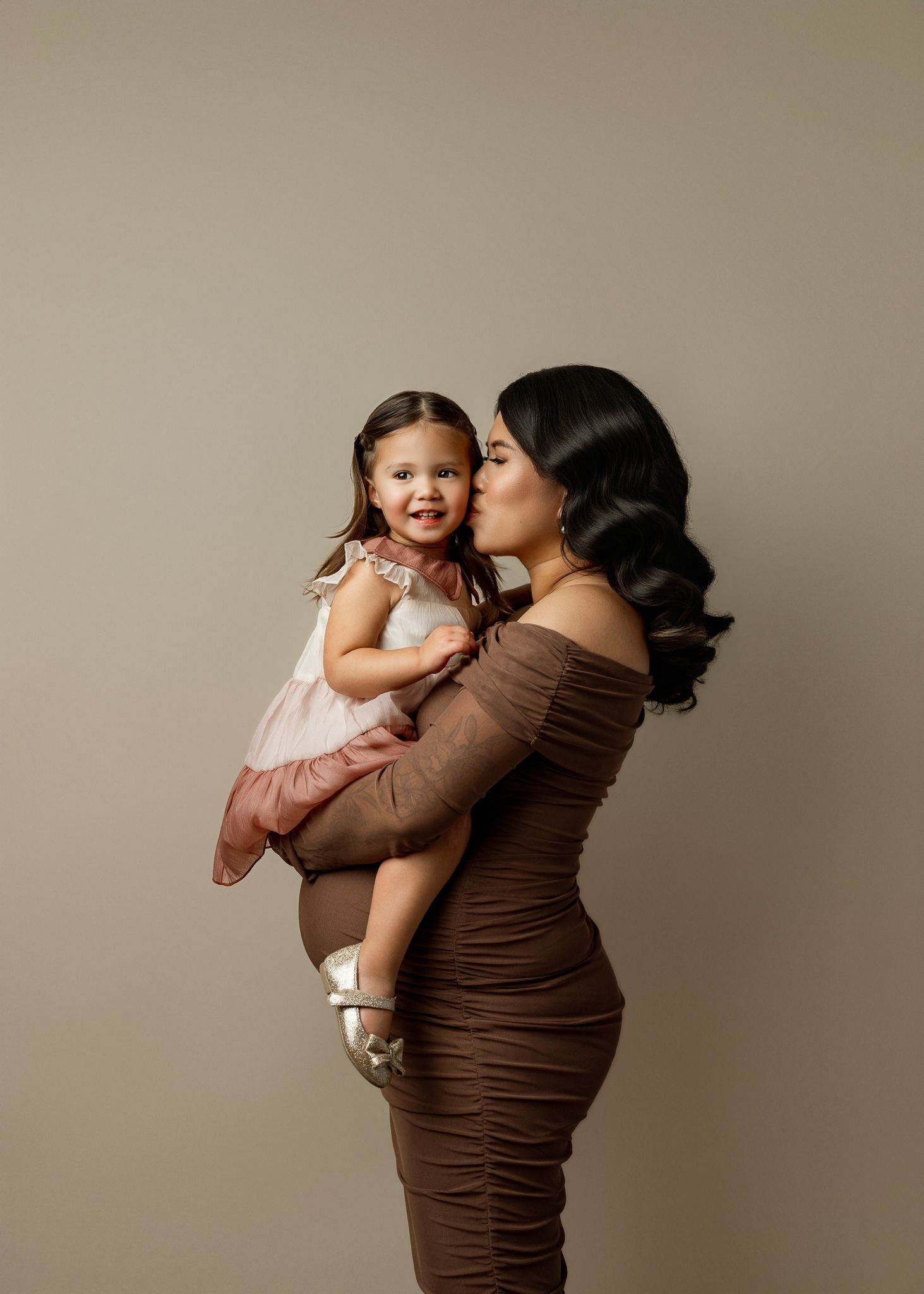 A series of tender moments between parent and child in brown and pink outfits against a neutral backdrop.
