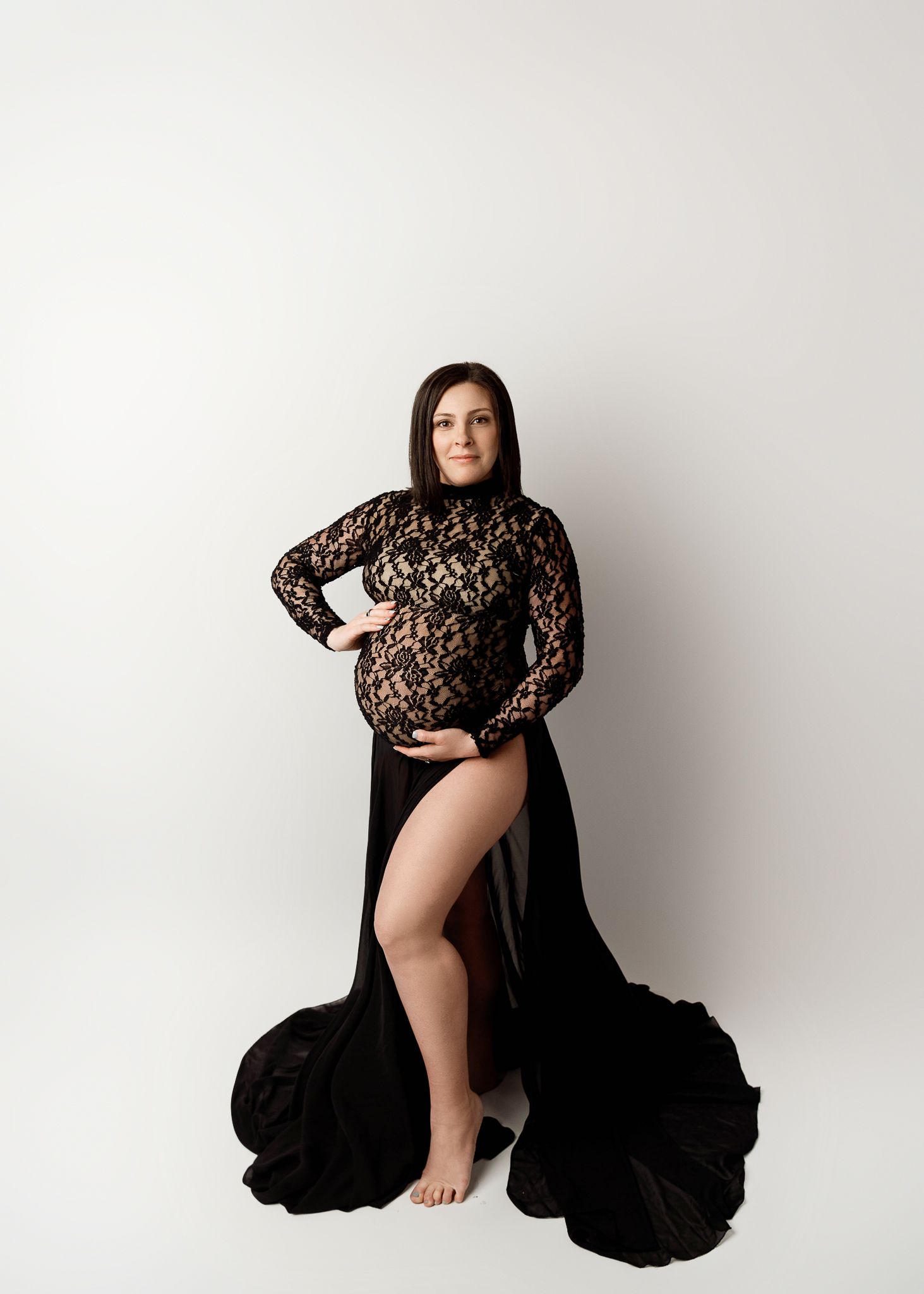Studio maternity portrait in black lace gown with dramatic flowing train.