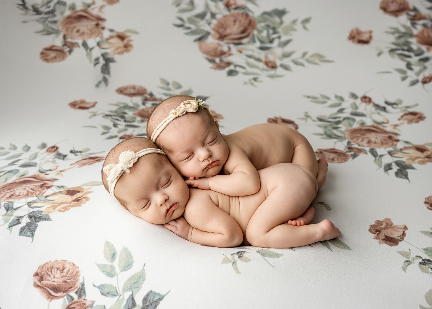Newborn baby sleeping peacefully on floral backdrop in multiple artistic poses.