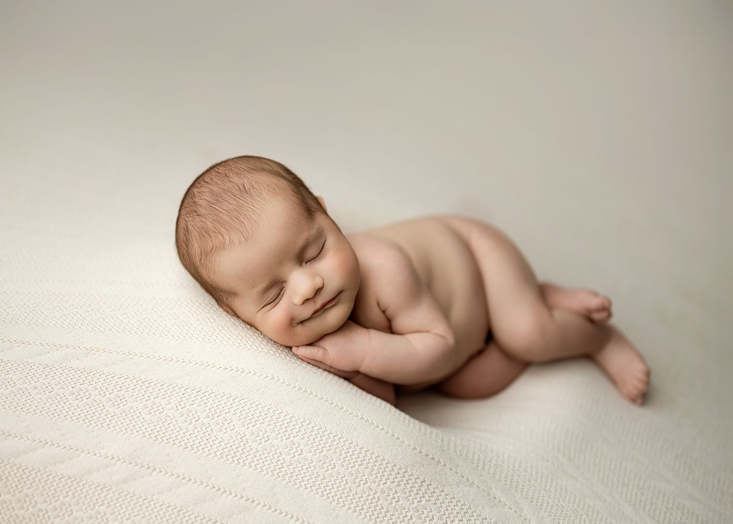 A series of artistic newborn baby portraits showing gentle poses on soft white textured backgrounds.