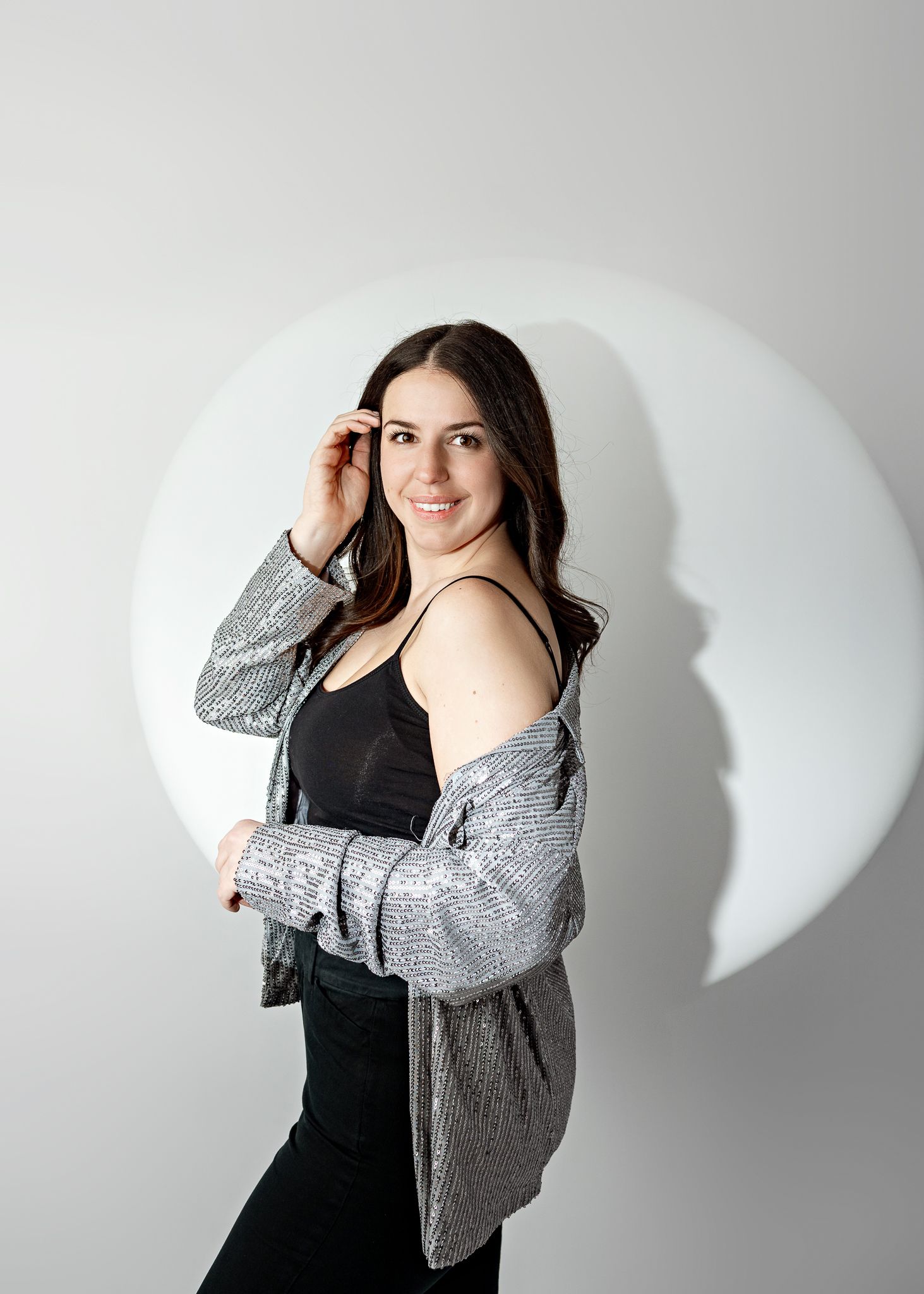 Figure in a black tank top and gray cardigan poses against white background with a circle design.