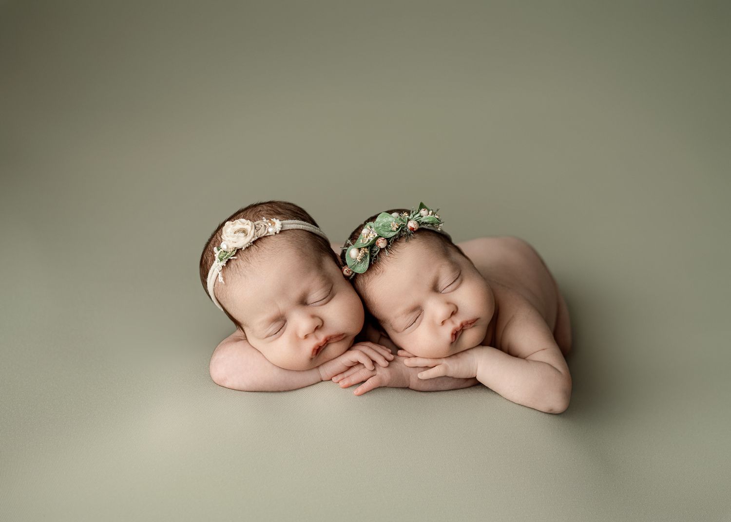 Seven minimalist newborn portraits on sage green background show sleeping baby in various peaceful poses.