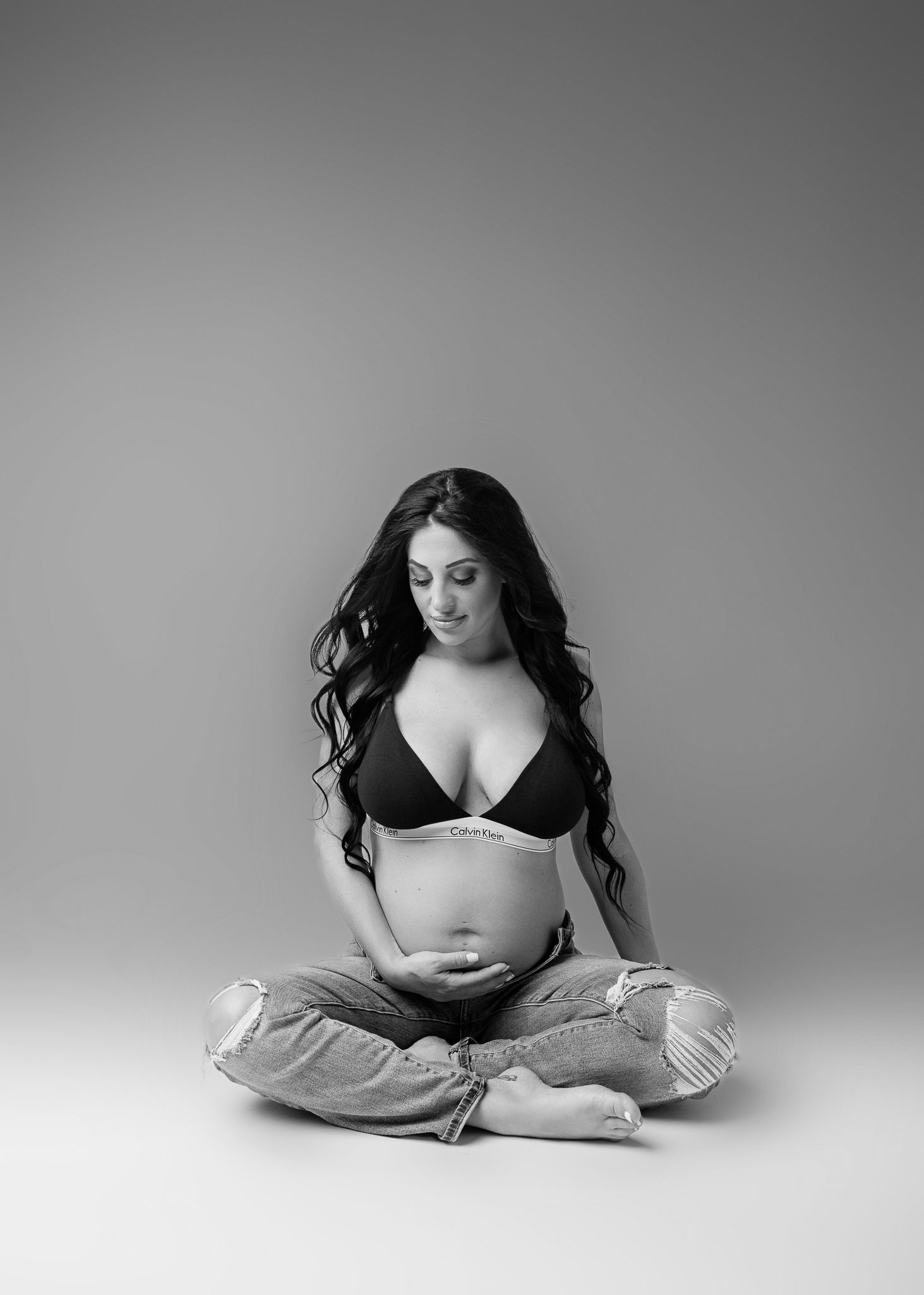 Black and white maternity portrait in a peaceful meditative seated pose.