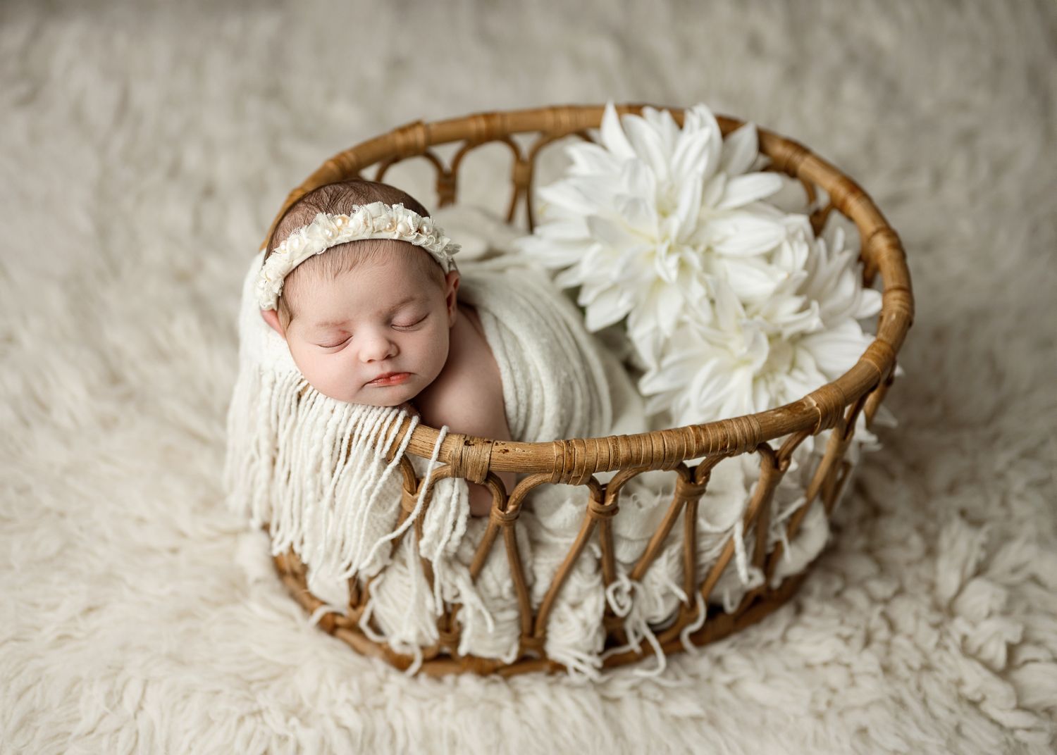 Newborn photography collage showing sleeping baby in woven basket with white floral decorations on textured backdrop.