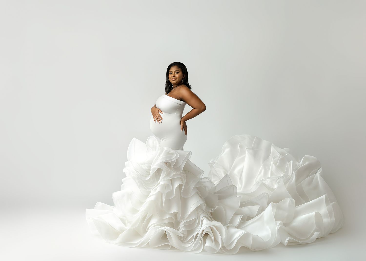 A stunning white wedding gown with dramatic ruffled skirt photographed against a minimal white background.